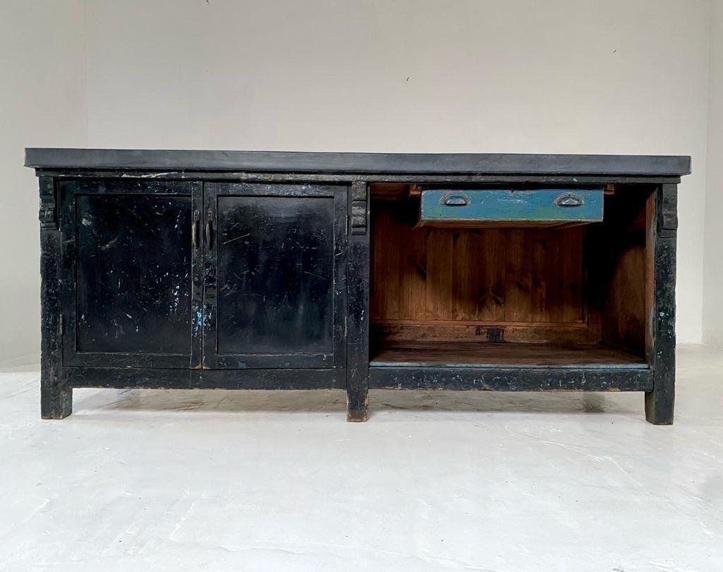 Great looking vintage industrial workbench with an aged zinc top.

This is a really practical piece with a two door cupboard on the left, a drawer with original brass handles and a potting shelf below. We have replaced the old back boards with new