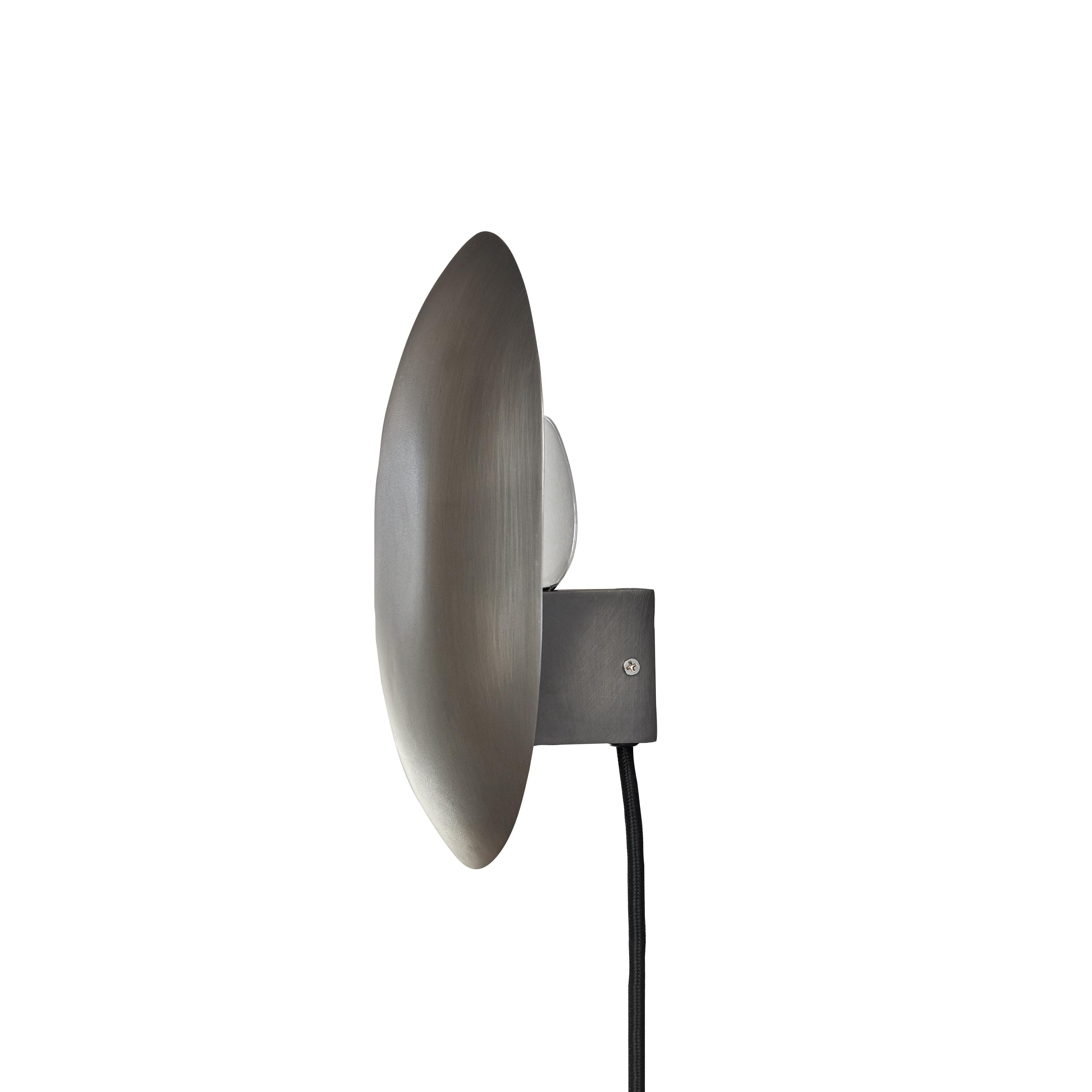 Zink clam wall lamp by 101 Copenhagen
Designed by Kristian Sofus Hansen & Tommy Hyldahl
Dimensions: L 14 x W 22 x H 26 cm
Cable length: 170 cm
This product is not wired for USA
Materials: metal: plated metal / zink
Cable: fabric covered cable /