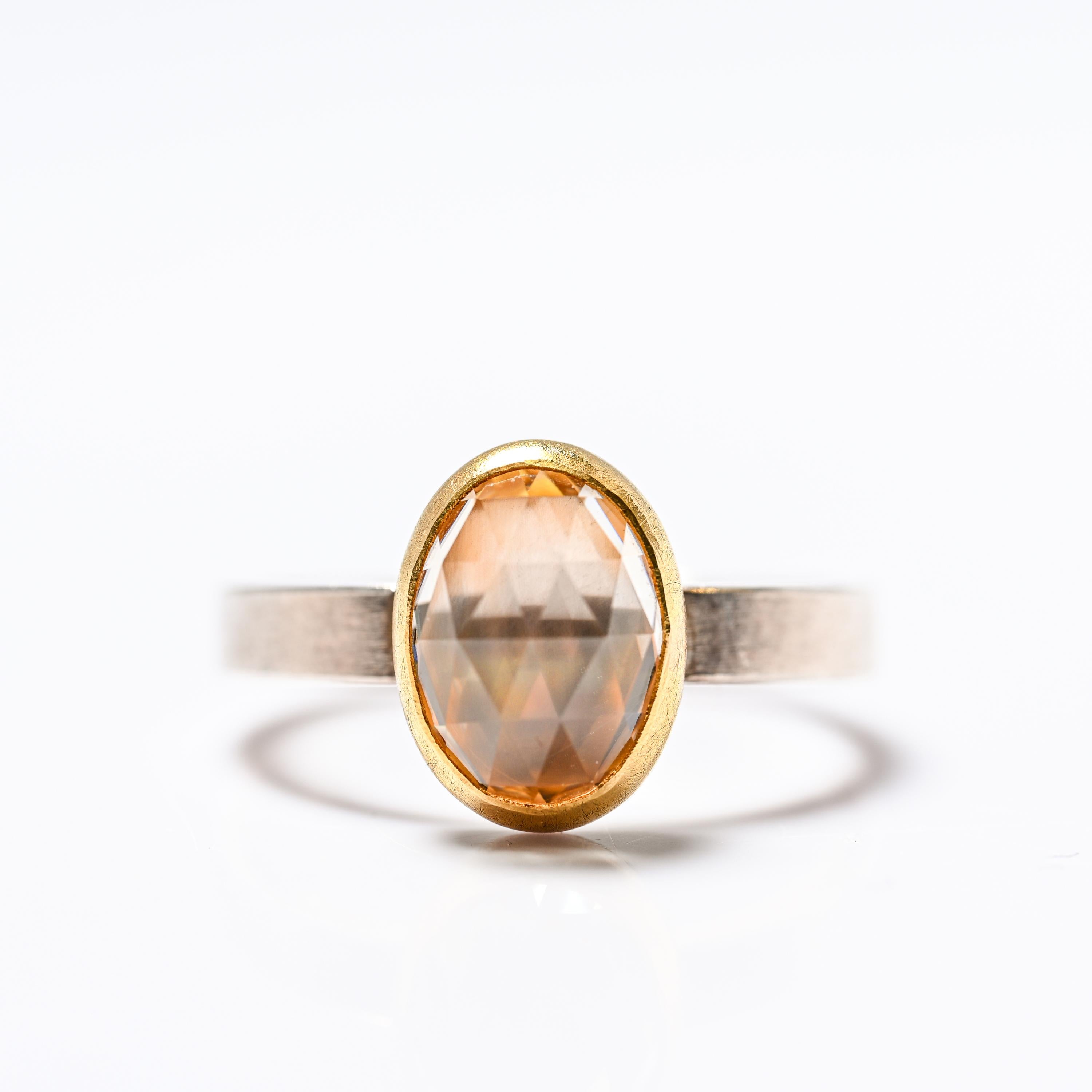 Una splendida gemma ovale a cupola di zircone naturale con taglio a rosa è incastonata in una montatura in oro giallo satinato a 22 carati, appollaiata su una fascia di spesso argento sterling spazzolato.  Lo zircone ha un'incastonatura chiusa,