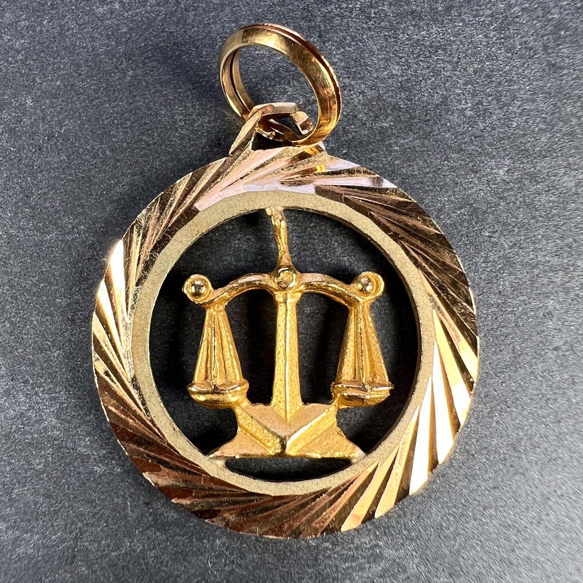An 18 karat (18K) yellow gold charm pendant designed as a ridged frame surrounding a pair of balance scales representing the zodiac starsign of Libra. Stamped with the owl mark for 18 karat gold and French import.

Dimensions: 2.7 x 2.4 x 0.25 cm