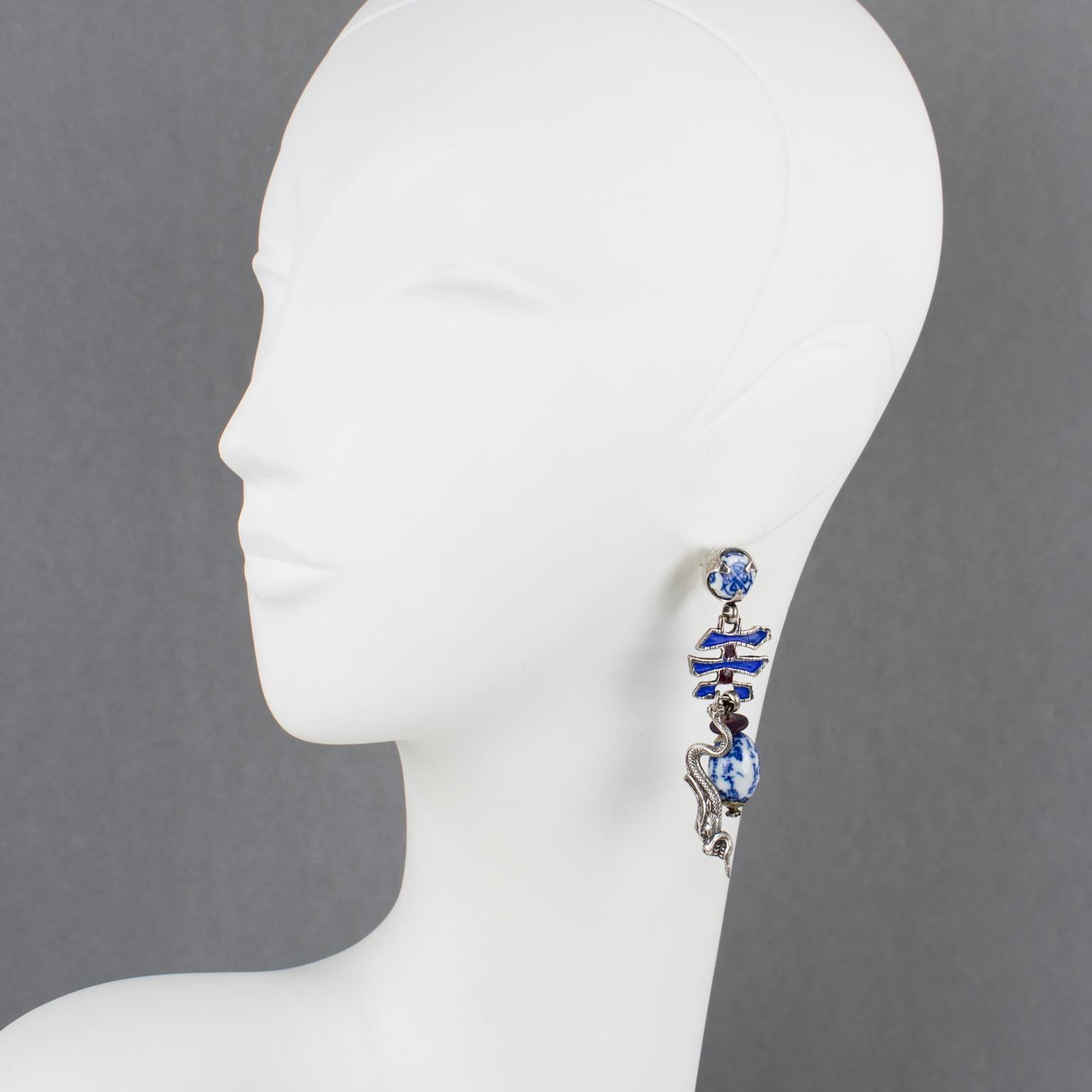 These stunning Zoe Coste dangle pierced earrings were hand-crafted in France in the 1980s. They have an Asian-inspired design with a textured silvered metal ideogram ornate with blue enamel, accented with Asian blue ceramic drop beads, cabochons,
