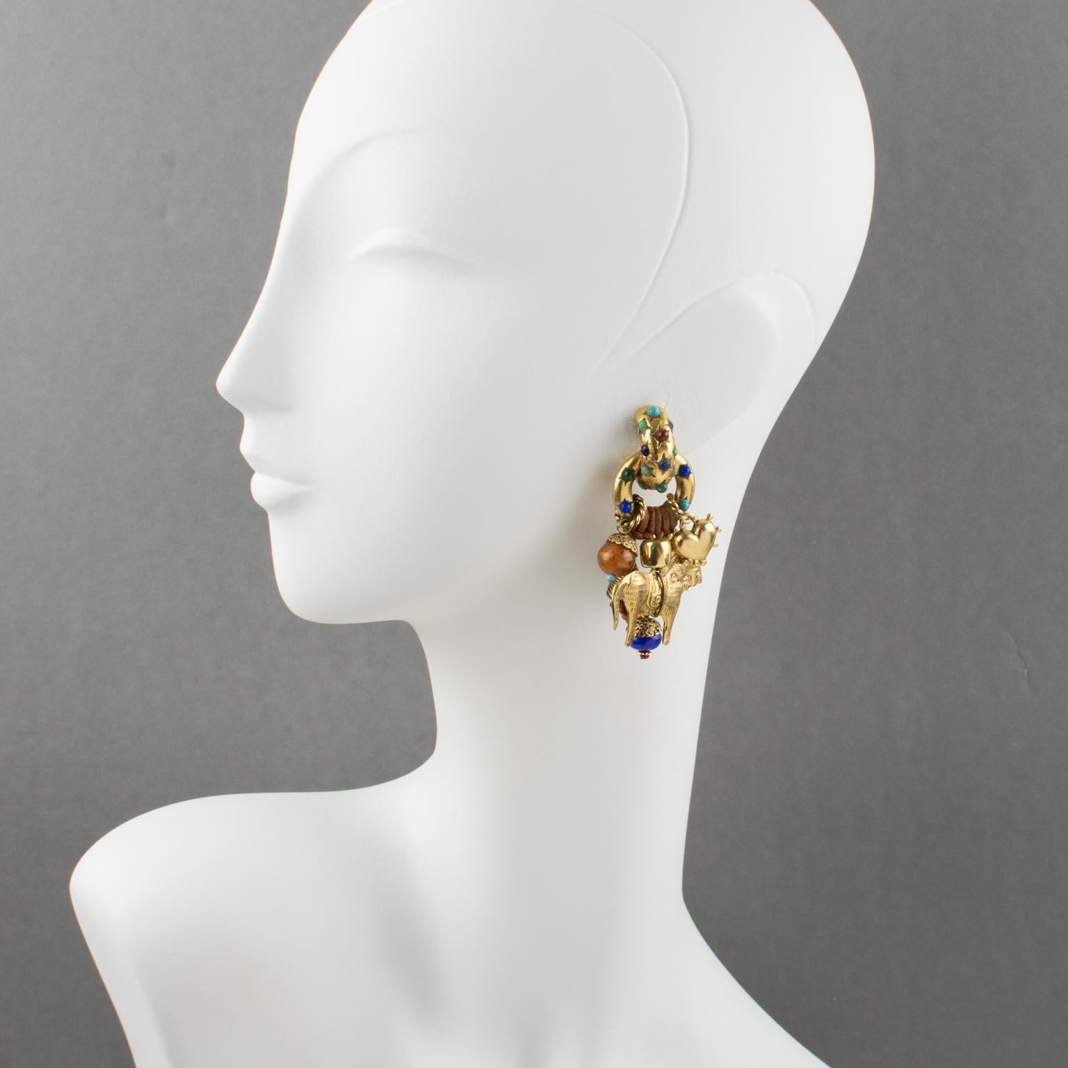 Superbes boucles d'oreilles clip Boho chic de Zoe Coste. Flair dramatique avec un design ethnique en métal doré, tout en textures ornées de charmes pendants attachés à des liens en cuir (cheval, cœur, perles), et surmontés de minuscules cabochons en