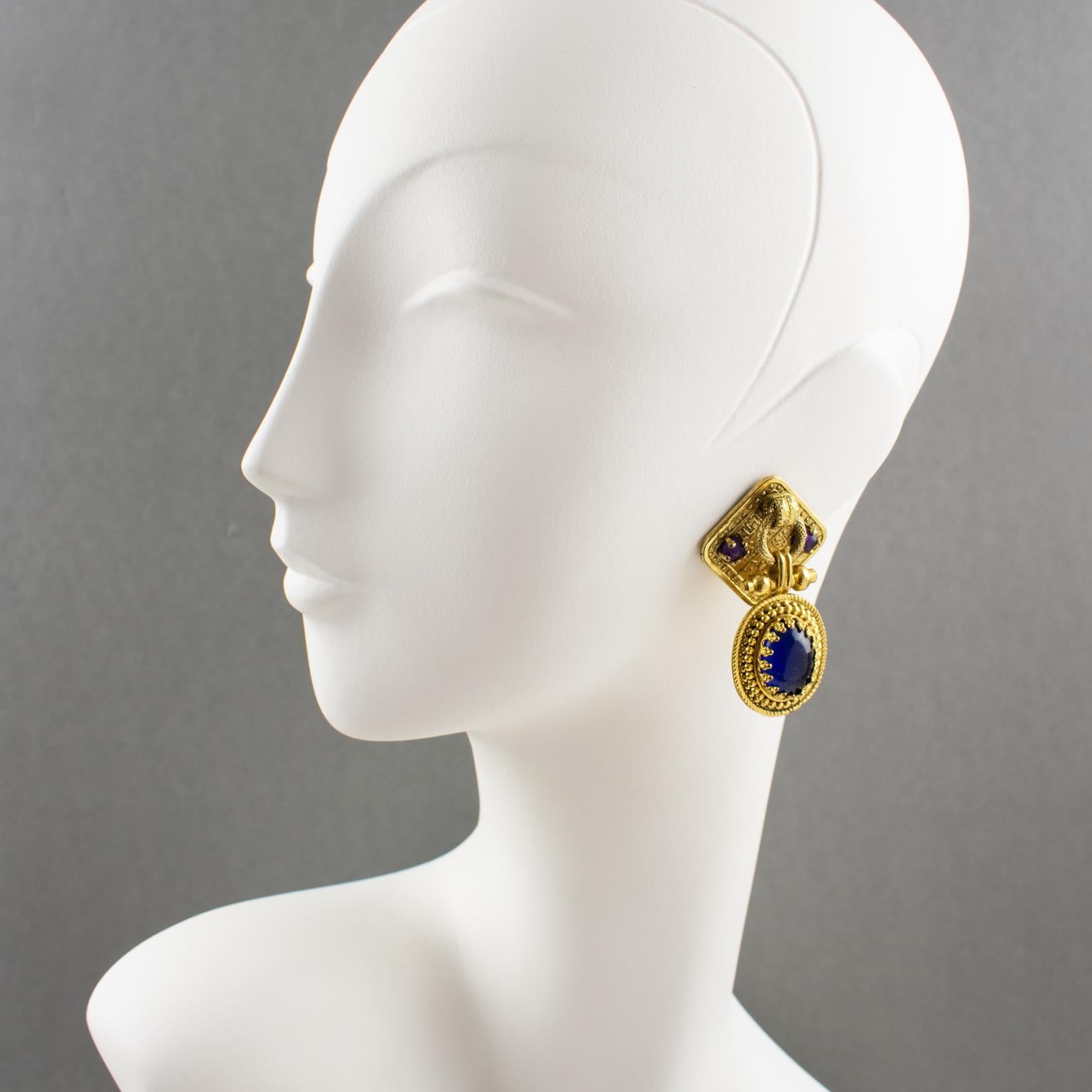 Thrilling Zoe Coste for Reminiscence gilt metal dangling clip-on earrings. Featuring geometric door-knocker shape with gilt metal all textured ornate with cobalt blue and purple poured glass cabochon. Marked underside with company logo: