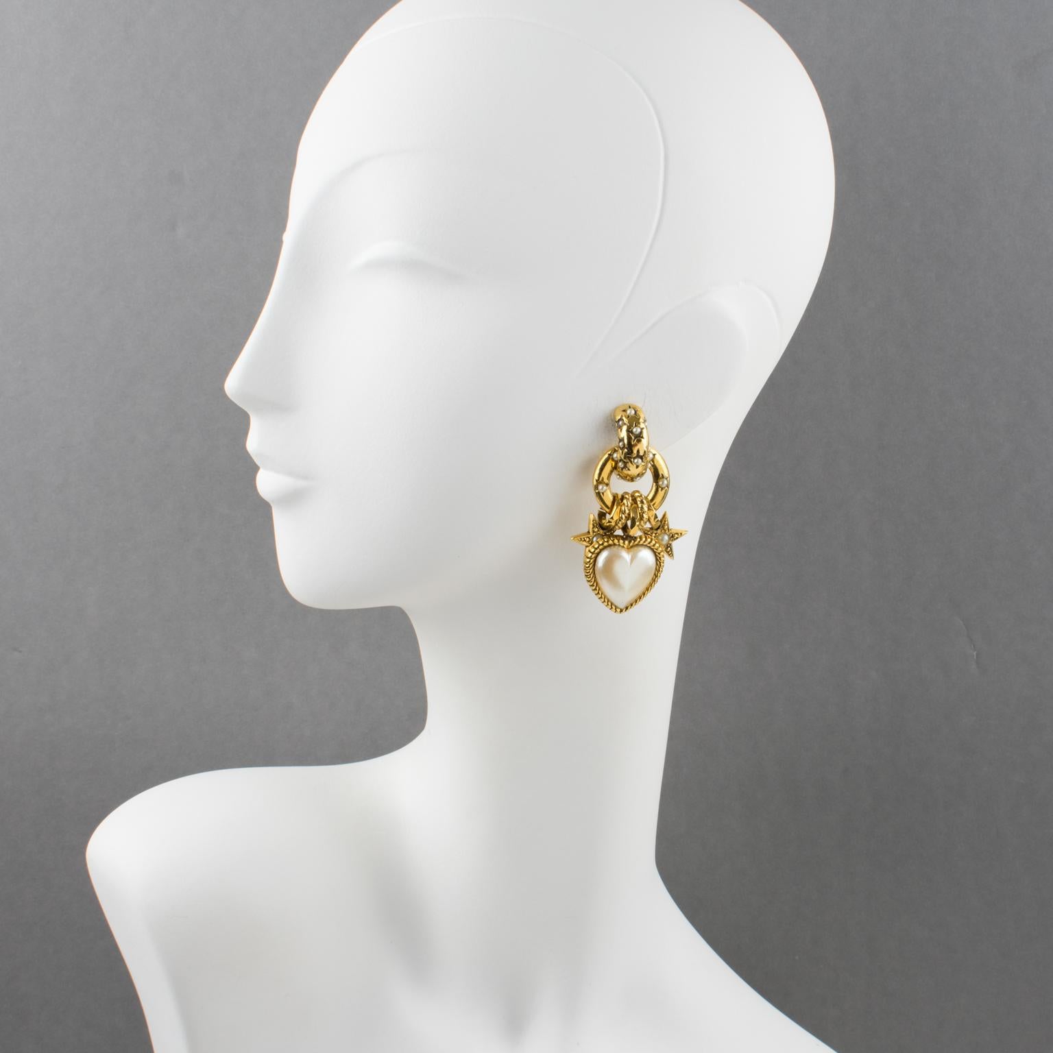 Lovely Zoe Coste romantic dangling clip-on earrings. Dramatic flair featuring heart and star design with gilt metal all textured ornate with dangling charms (heart, star, ring) and topped with pearl-imitation tiny glass cabochons. Central huge heart