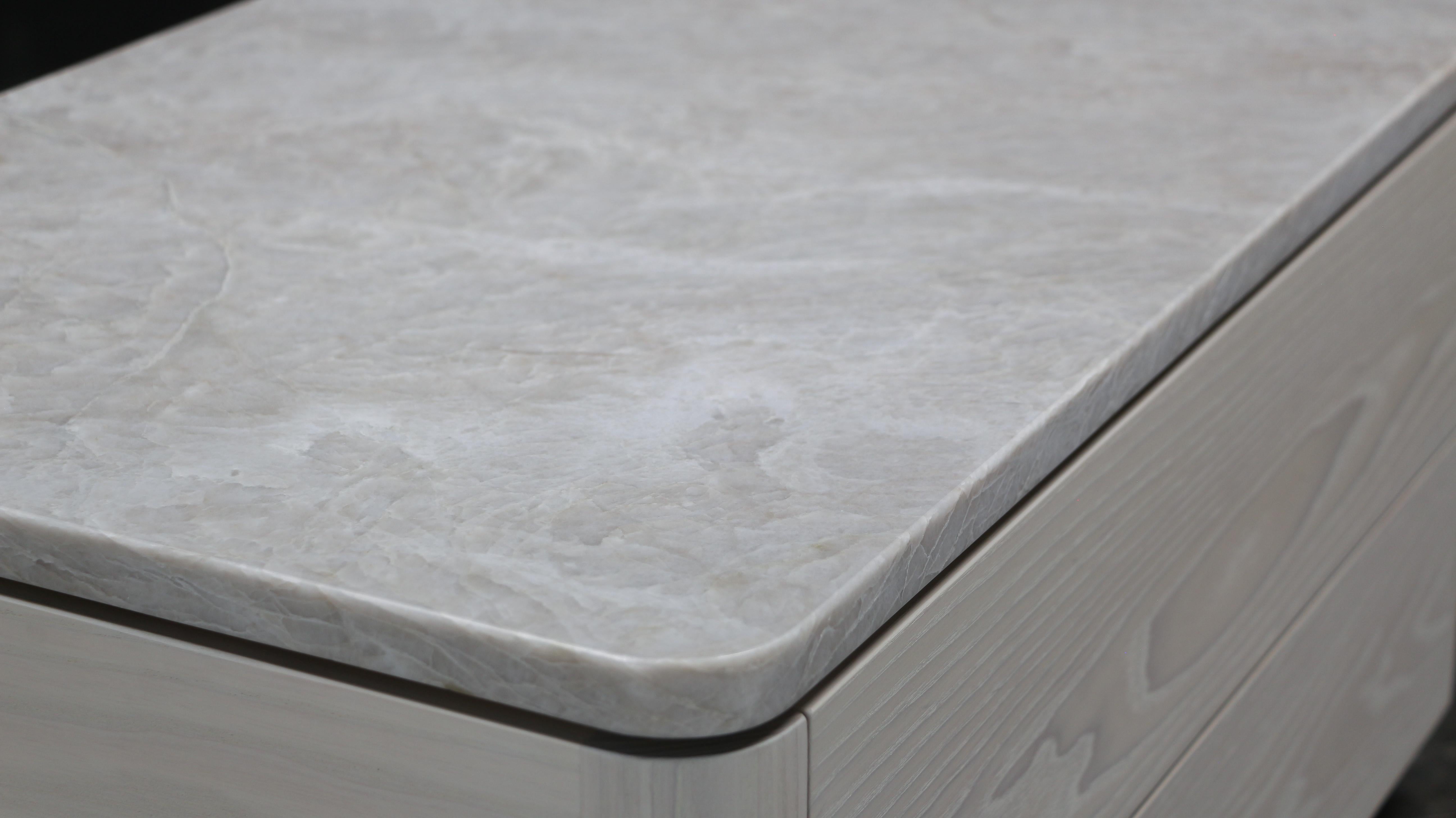 La table de nuit ZOË est faite sur mesure pour ranger avec élégance vos objets quotidiens et spéciaux. Avec ses tiroirs en bois massif doublés de placage de daim et son design flottant, il respire le luxe. Personnalisez votre commande avec des