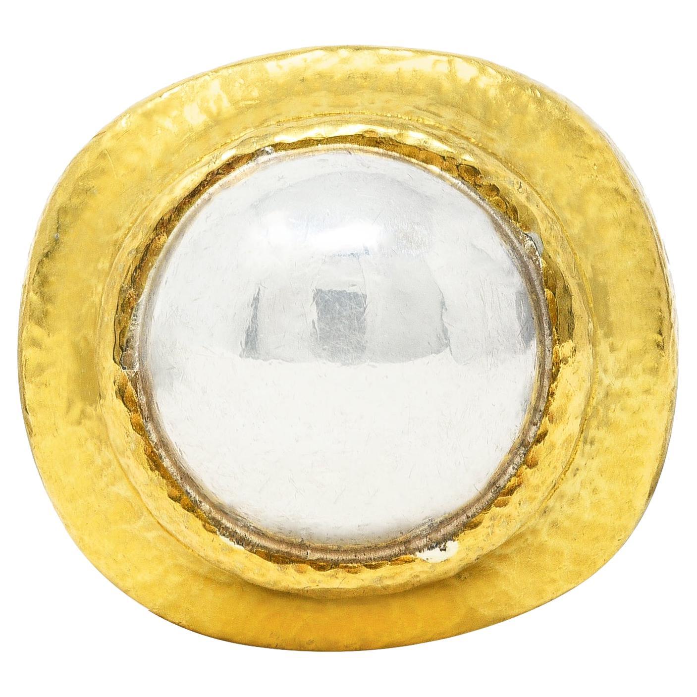 Centering a 13.3 mm round platinum dome with high polished finish. Bezel set with a recessed cushion shaped surround. Featuring a fine hammered texture throughout. Stamped for 22 karat gold and platinum. Numbered and signed Zolotas. Circa: 1980's.