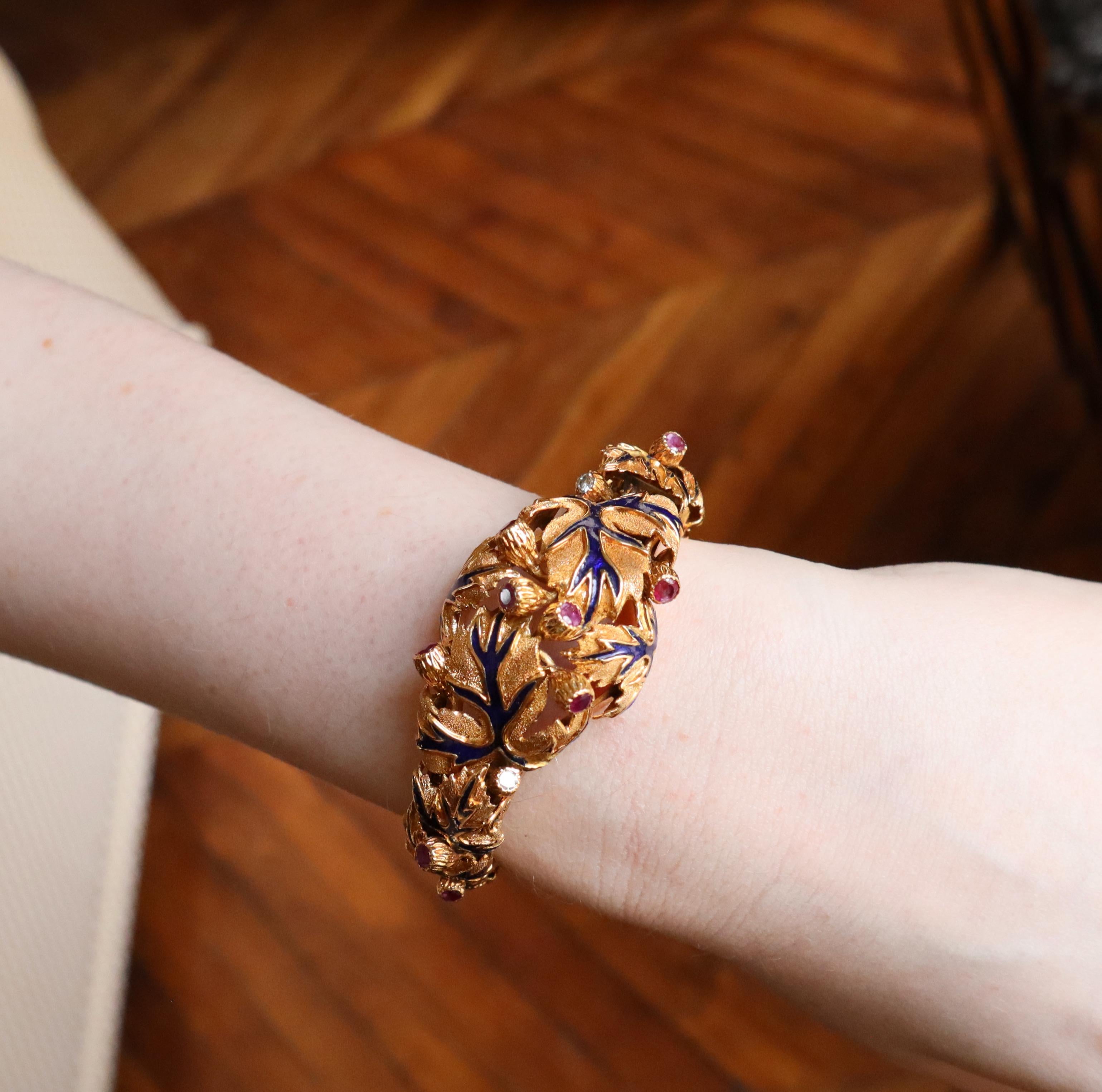 ZOLOTAS Armband aus gemeißeltem 18-karätigem Gelbgold mit blauem Emaille-Blattmotiv und Rubinen und Diamanten. Das Armband ist an zwei Stellen mit einem Federmechanismus aufklappbar, so dass es am Handgelenk getragen werden kann. Das Armband zeigt