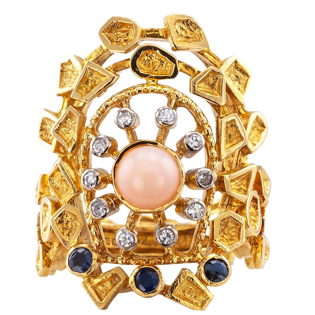 Zolotas coral diamond and sapphire gold ring. The organic 18-karat gold design centers upon a round angel skin coral encircled by ten radiating round diamonds totaling approximately 0.10 carat, all balanced by three similarly shaped blue sapphires,