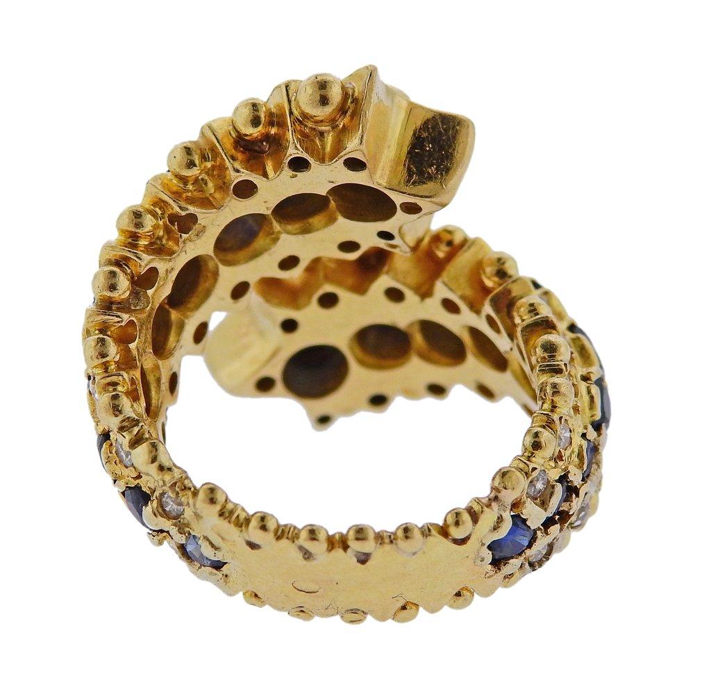 Vintage 18k gold bypass ring by Zolotas Greece, set with approx. 0.30ctw H/VS diamonds and sapphires. Ring size - 6, ring top measures 24mm wide. 
Weight: 15.4 grams. Marked:  E 54, 750, Zolotas. 