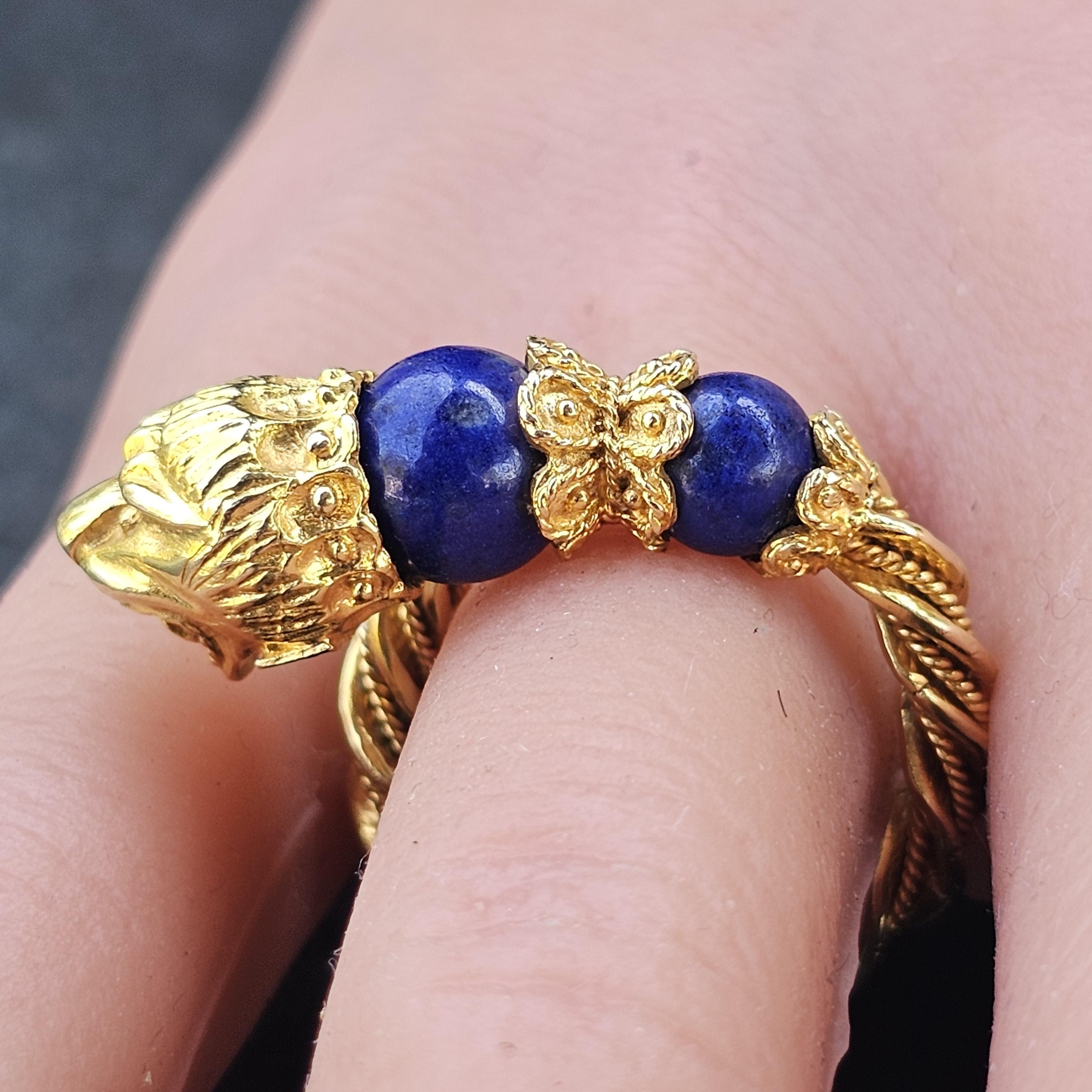 Questo straordinario anello è una creazione magistrale di Zolotas. Realizzato in oro giallo 18 carati, presenta un audace design a testa di leone con dettagli intricati. La fascia è ornata da vibranti pietre di lapislazzuli, che aggiungono un ricco