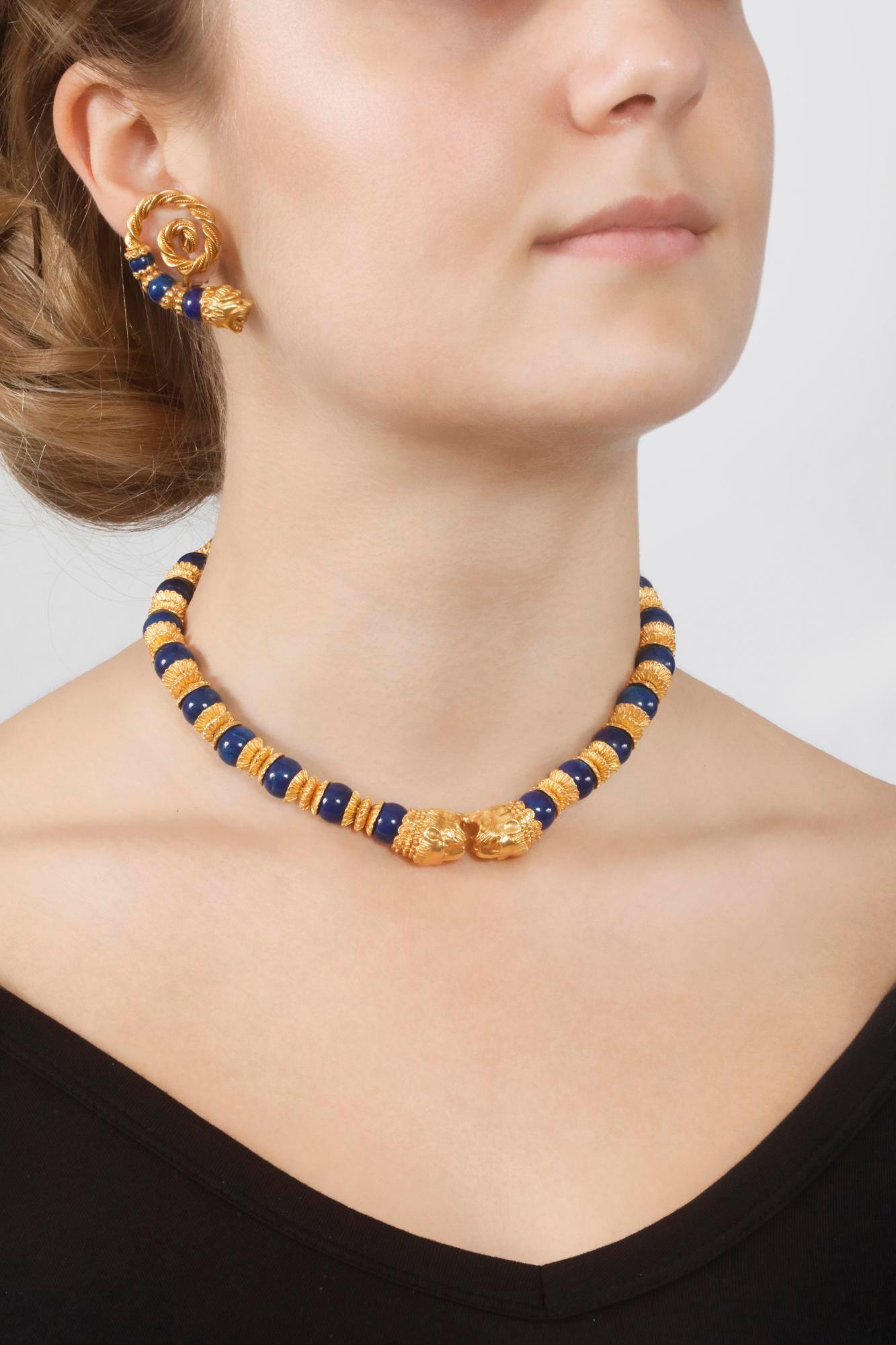 A beautiful demi-parure by Zolotas comprising a necklace composed of lapis lazuli spheres alternating with structured gold separators, the front embellished with lion head motifs. Length approximately 360mm, French import assay mark for gold; and a