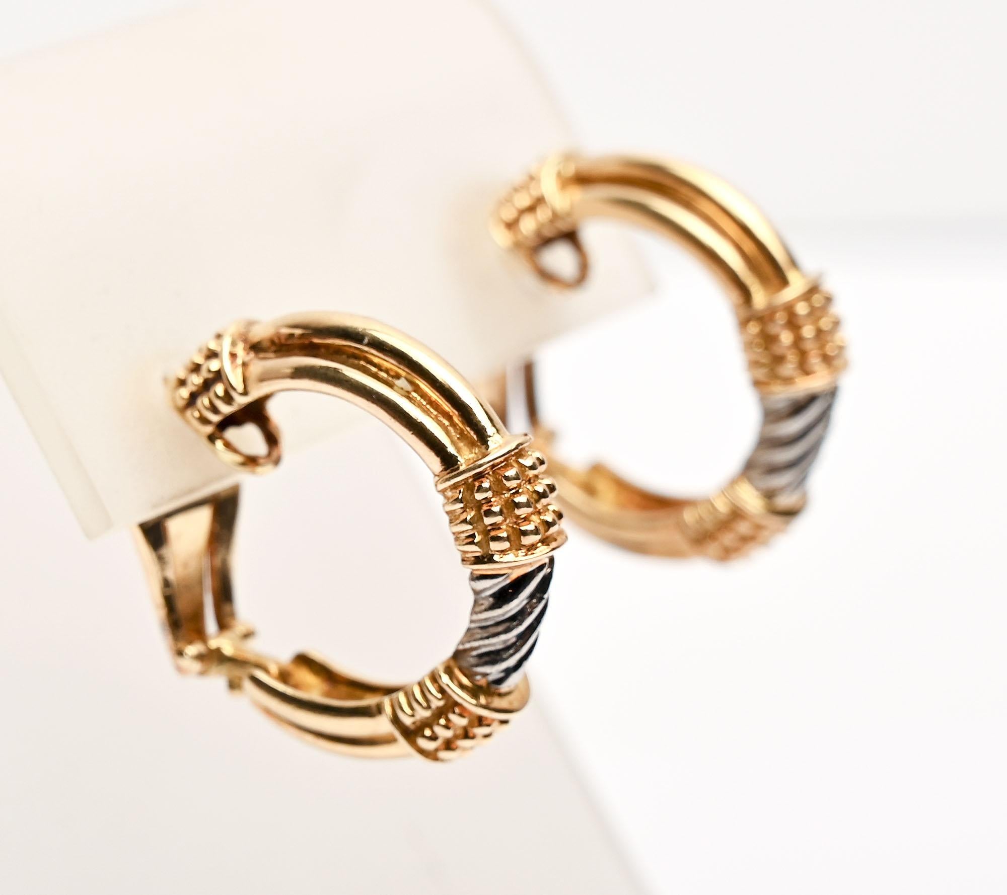 Two features add interest  to these hoop earring by Zolotas. They are both yellow and white gold and have two different textures. The white gold centers have a ribbed, swirl design. On either side of the white gold are small raised balls. They