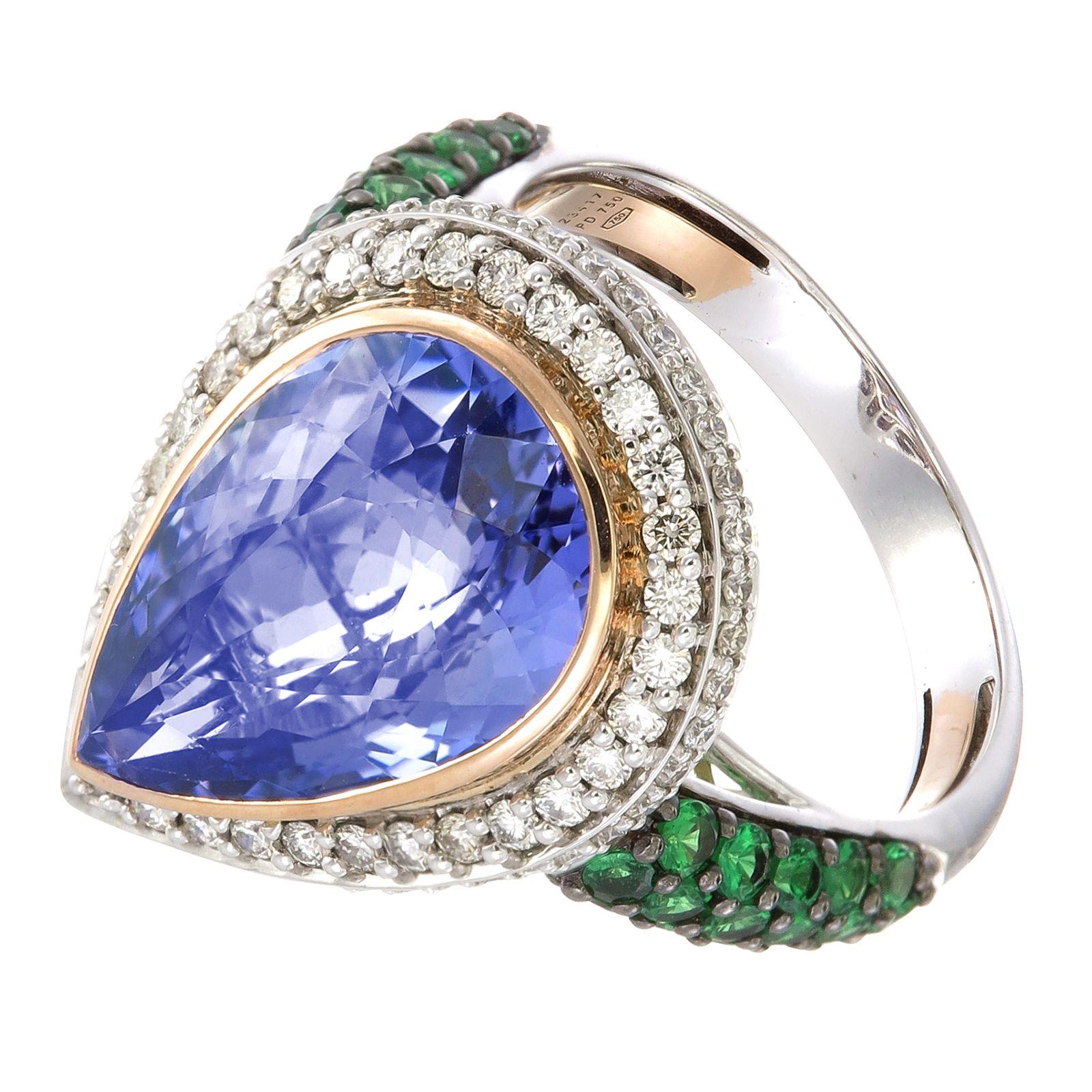 A 9.75-tear-shaped translucent Tanzanite is framed by sparkling 0.58-carat White Diamonds on a Palladium and 18K Gold ring. On each side of the shank is a minty splash of bright green from clusters of 0.93-carat Tsavorite Garnet. An adjustable gold