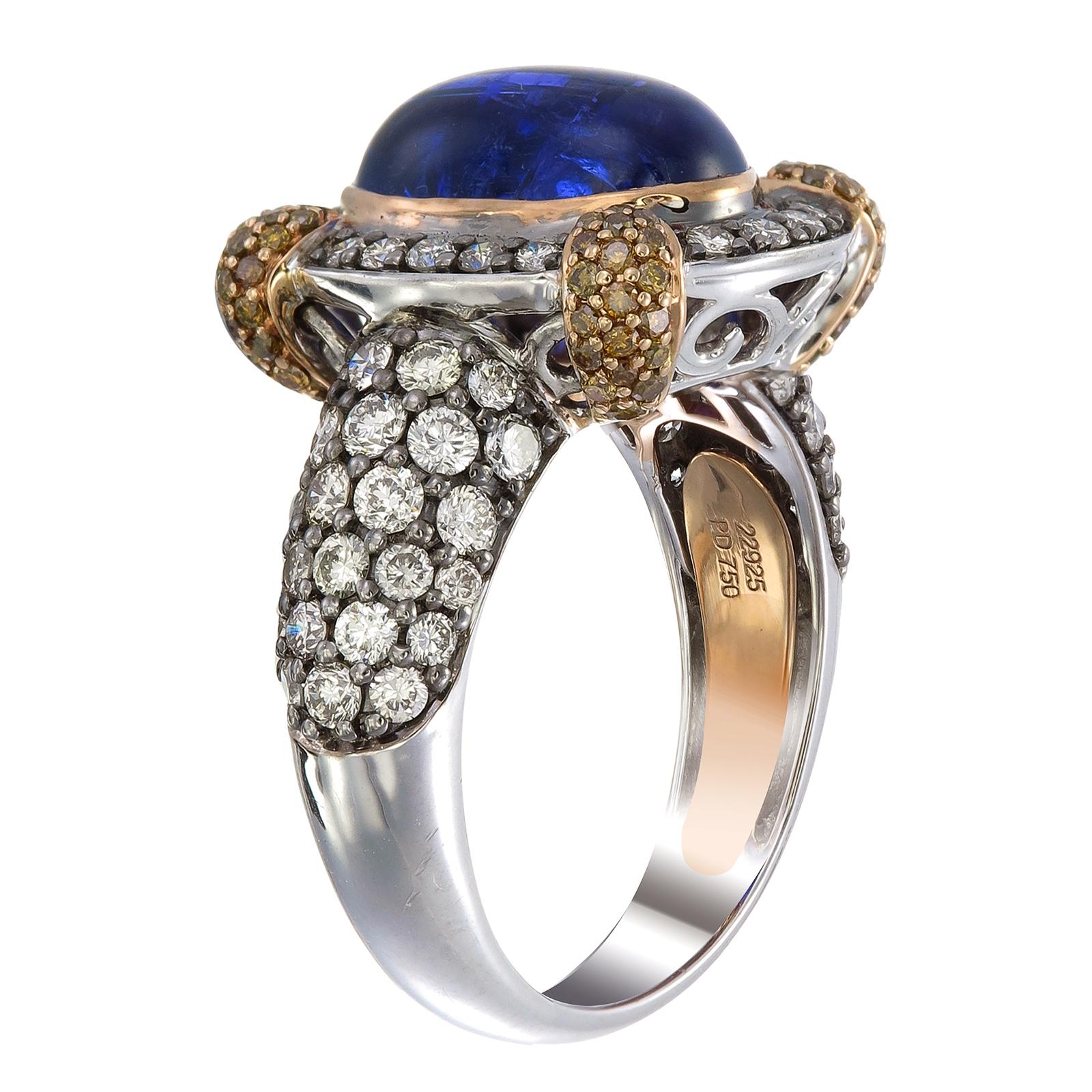 Auf einem Thron aus Gold und Diamanten sitzt ein blauer Tansanit von 6,81 Karat, der von Zacken gehalten wird, die mit 0,47 Karat Fancy-Diamanten besetzt sind. Die Schulter und der Schaft des Rings aus Palladium und 18-karätigem Gold sind mit runden
