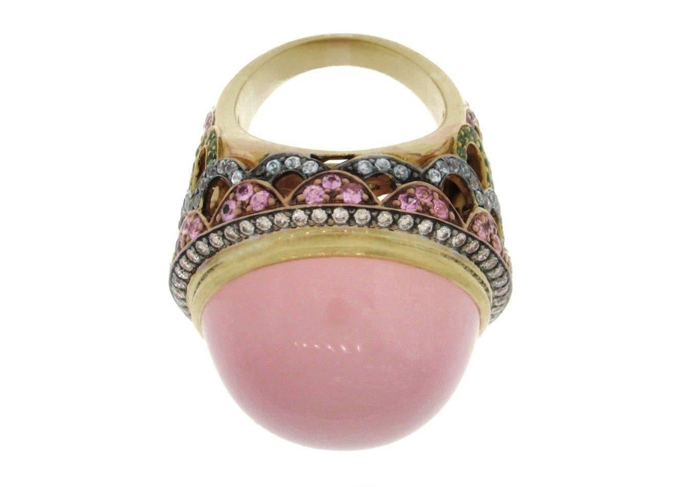 Large Statement Ring by Zorab featuring High Domed Rose Quartz Round Cabochon
surrounded by Round Brilliant Diamonds approx .75 ct, VS2-SI1 clarity, H-I color estimated.
Open Scalloped setting in 18k Yellow Gold featuring Pink Sapphires, Blue Topaz,