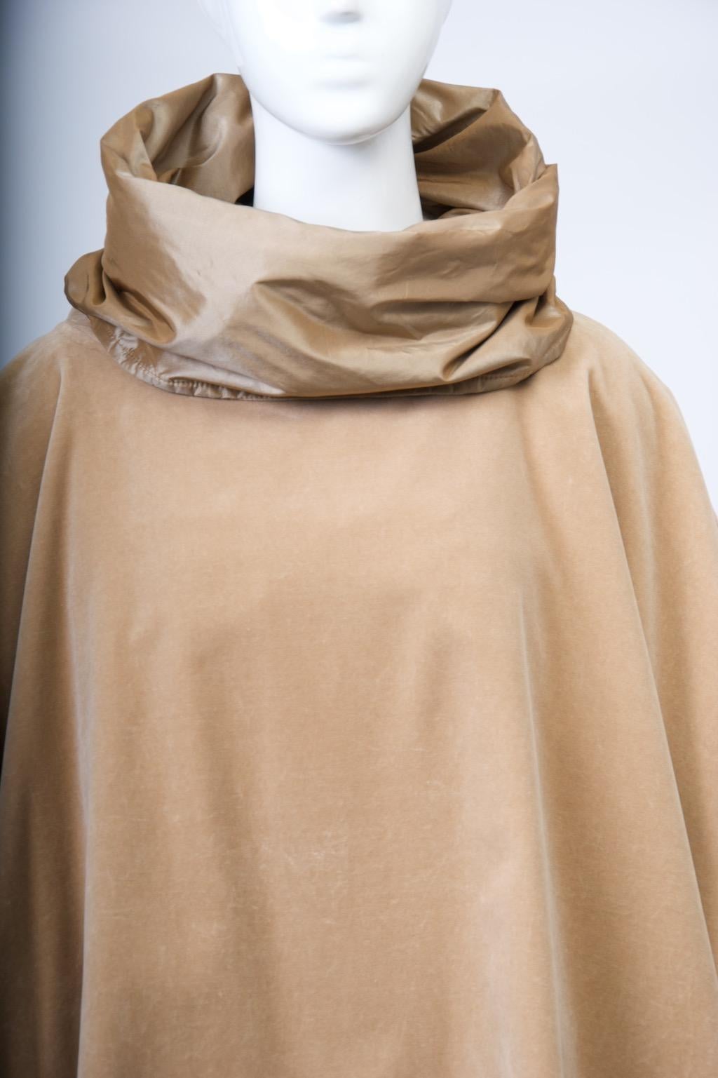 Il design moderno di Zoran trasforma il poncho in un elegante capo d'abbigliamento. Questo esemplare è realizzato in velluto di cotone color cammello foderato con una seta coordinata. Si distingue per il profondo collo a imbuto che, una volta