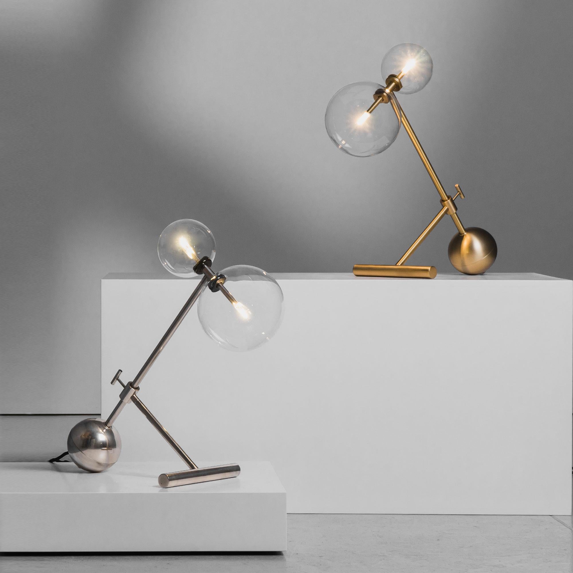 With a clear suggestive illumination, the Zosia table lamp elevates twin points of light upon thin rods, suspended within orbs of glass. A dynamic counterplay of weight and airiness, with the clean and stylish line of Mid-century Italian design. Two