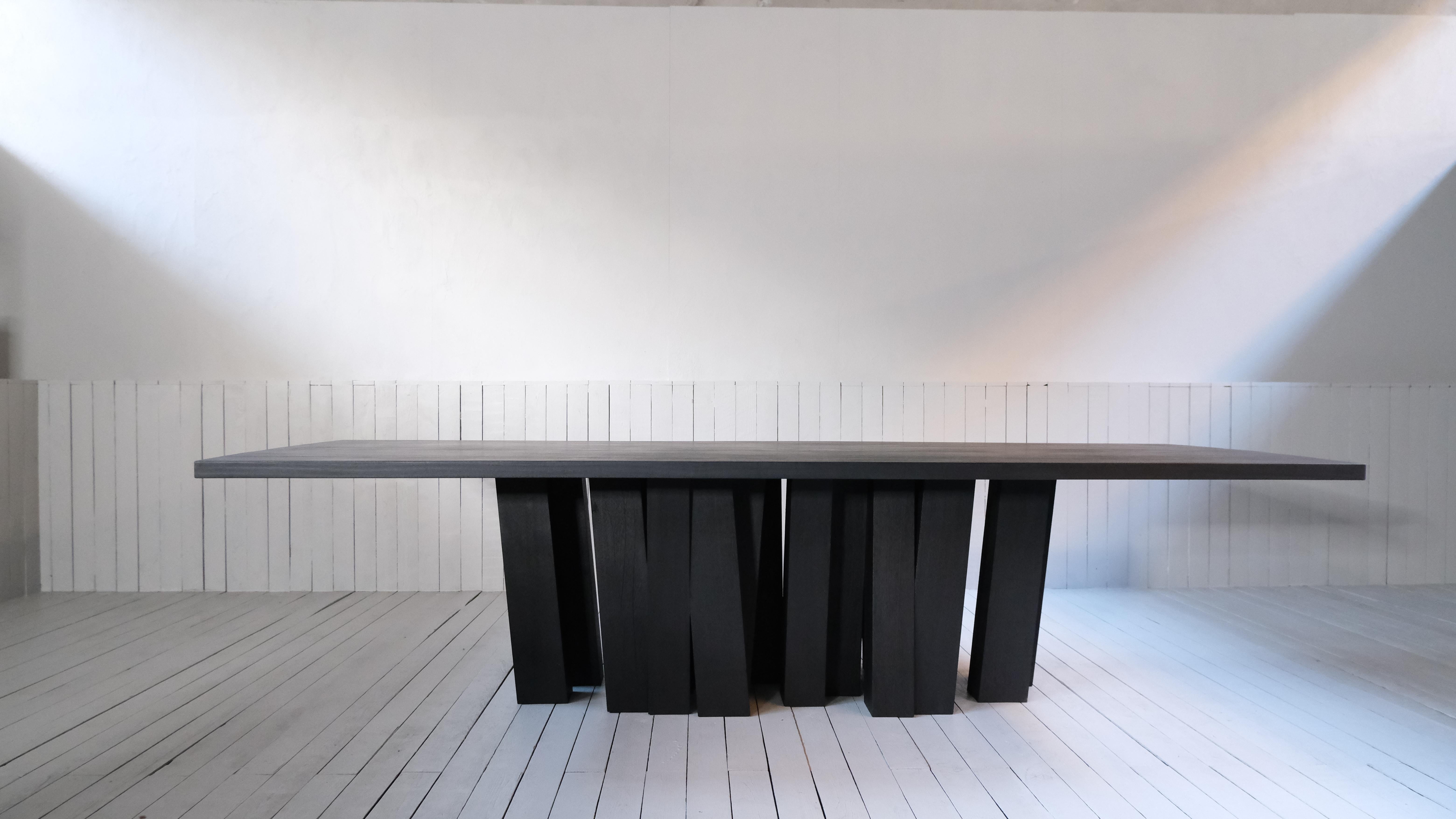Zoumey Large Base Table by Arno Declercq
Dimensions: W 300 x L 110 x H 75 cm 
Materials: A forest of table legs made out of 25 solid pieces of Iroko Wood 
 Table top made out of African walnut, burned and waxed. 

A dining table for 8 - 12