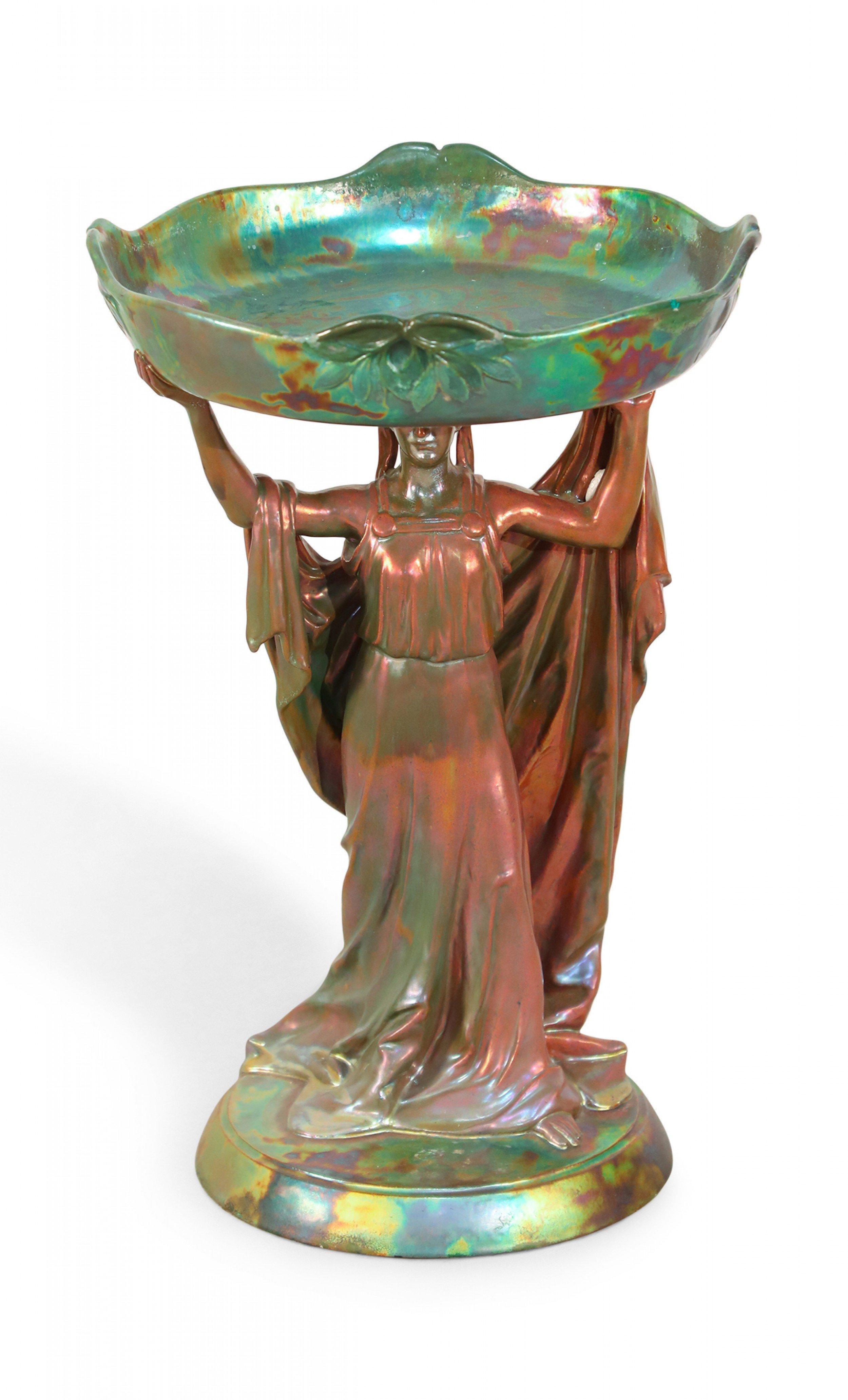 Art Nouveau Zsolnay porcelain green iridescent centerpiece with female figure holding round tray above head.
