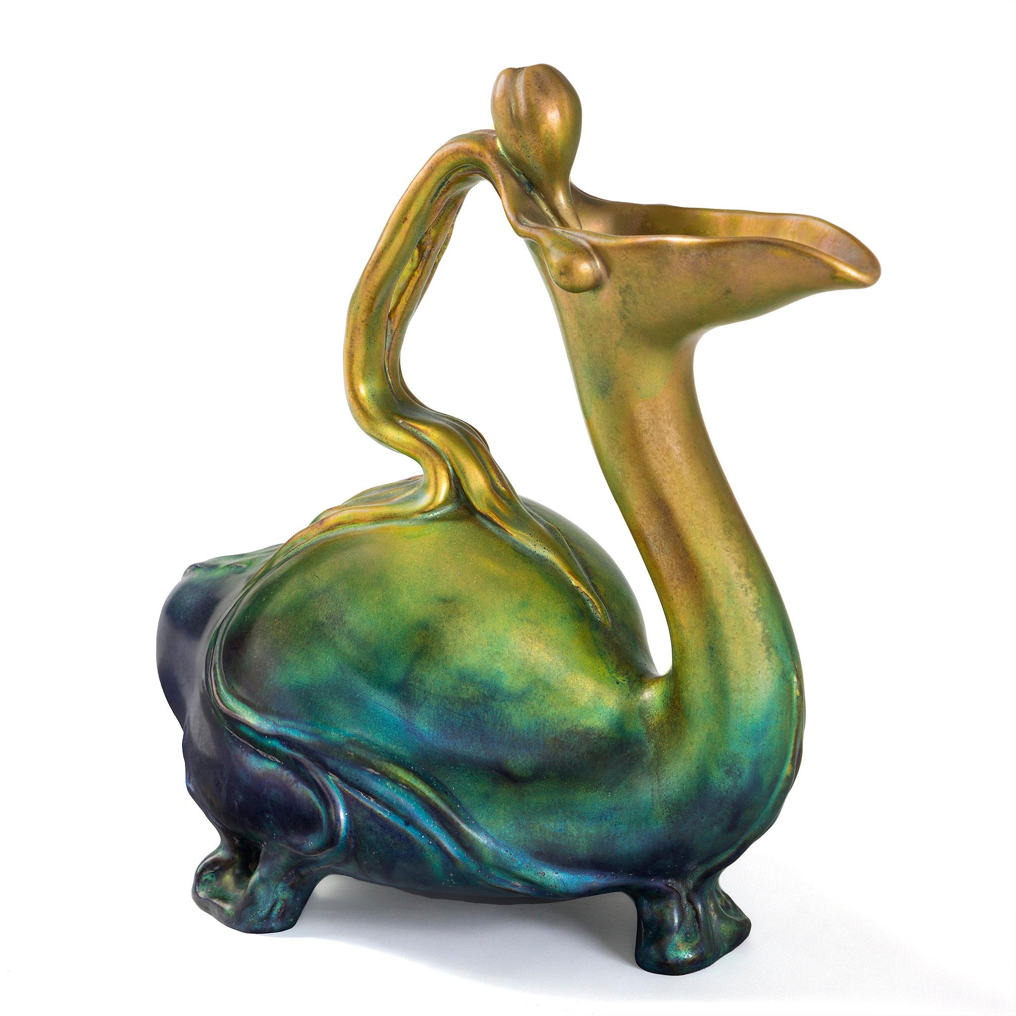 This resplendent Zsolnay bird ewer—resting on three feet and crowned with a blooming tulip handle—is a triumph of Art Nouveau design, created by Sándor Apáti-Abt for the Zsolnay manufactory. Its form draws inspiration from Bronze Age Hungarian
