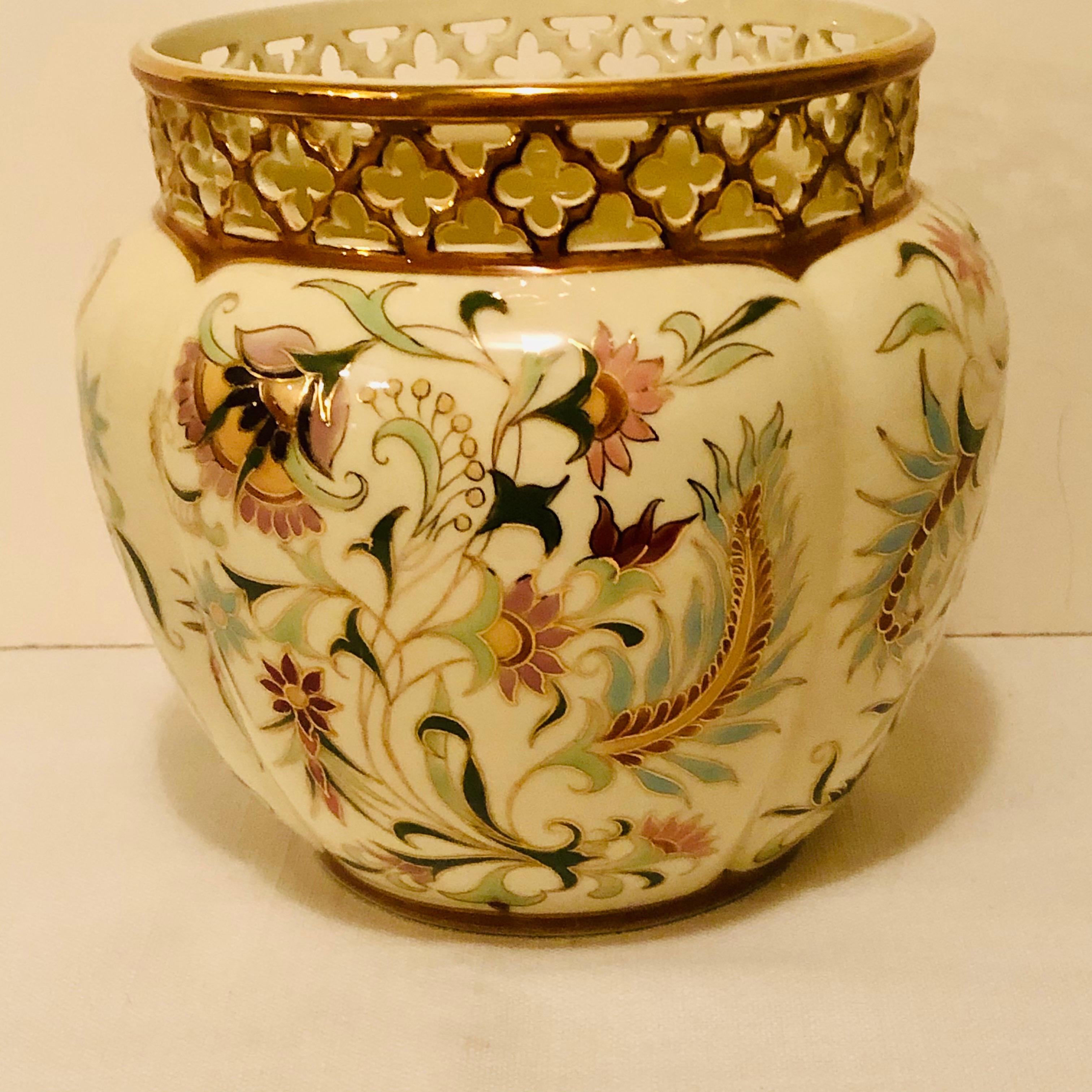 Wonderful Zsolnay jardinière painted with a wonderful colorful flower and leaf decoration in pink, green, purple, orange, maroon and yellow. The top of the jardinière has a lovely reticulated pattern around the top. It would be a stunning decoration