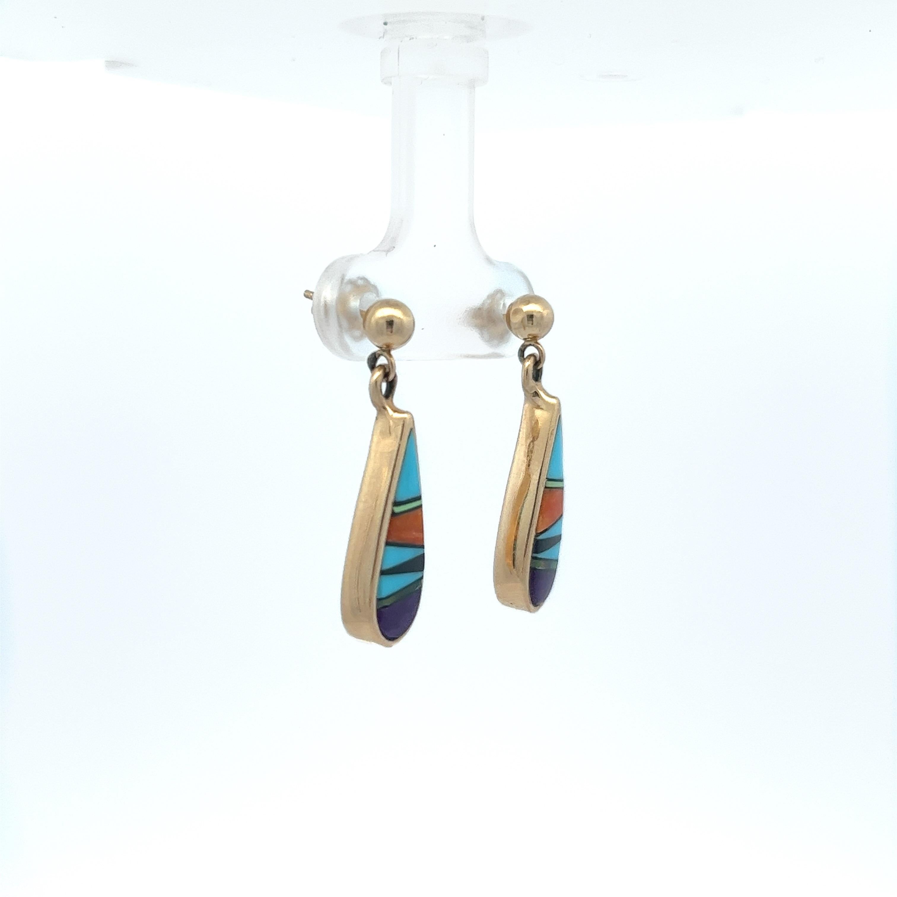 These multicolored Zuni inlay drop earrings are meticulously crafted from 14 karat yellow gold, featuring an exquisite combination of turquoise, sugilite, opal, onyx, and coral. The Zuni inlay method, a distinct feature in these earrings, is a