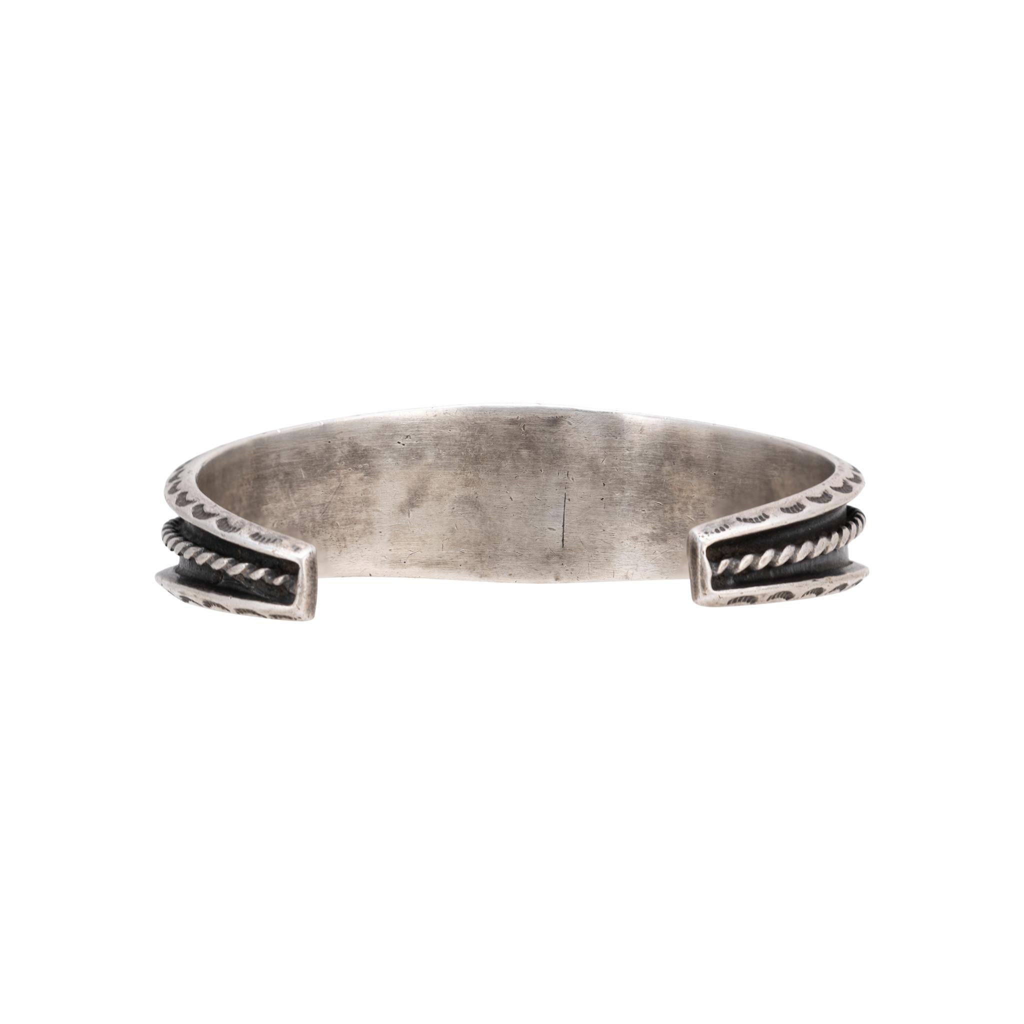 Bracciale in argento sterling con intarsio Zuni. Con pietre di taglio triangolare e quadrato di turchese e onice separate da linee di argento sterling. Attaccato a un delicato bracciale patinato con bordi stampati e accenti di corda intrecciata sui