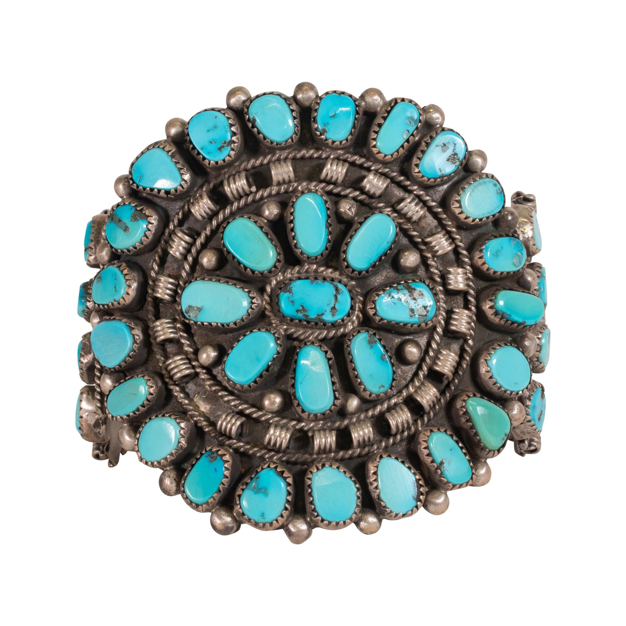 Large Zuni turquoise cluster bracelet. Total of 46 Kingman stones with bright blue color and minimal black and silver matrix. Accented with sterling bead, twisted rope, and coil detail. Great patina and weight. Perfect statement piece for formal or