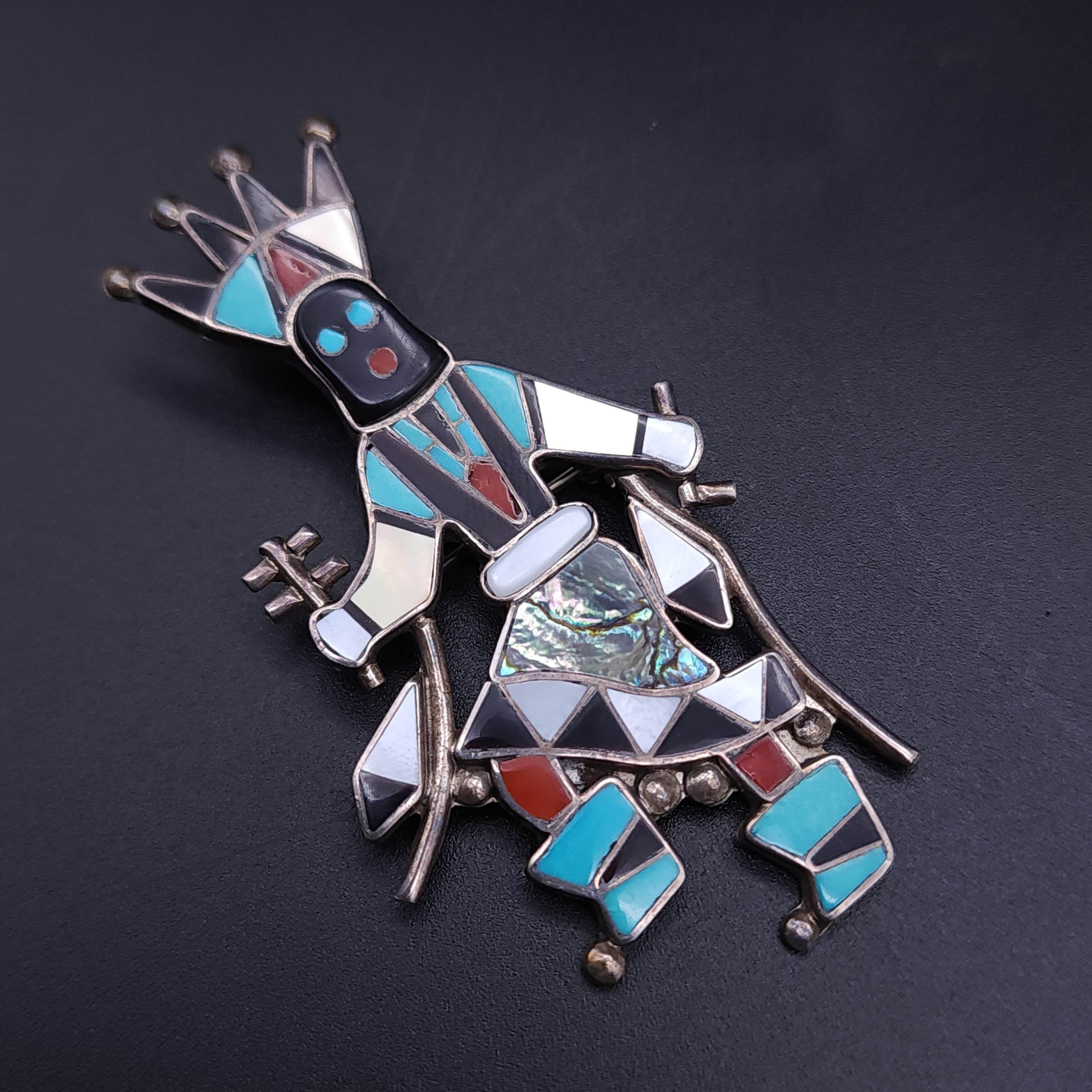 Embrace the rich cultural heritage with this meticulously crafted Zuni Native American Gan Dancer pin/pendant. This stunning piece features a traditional Gan Dancer, symbolizing the revered messengers between the human and spirit world. Set in