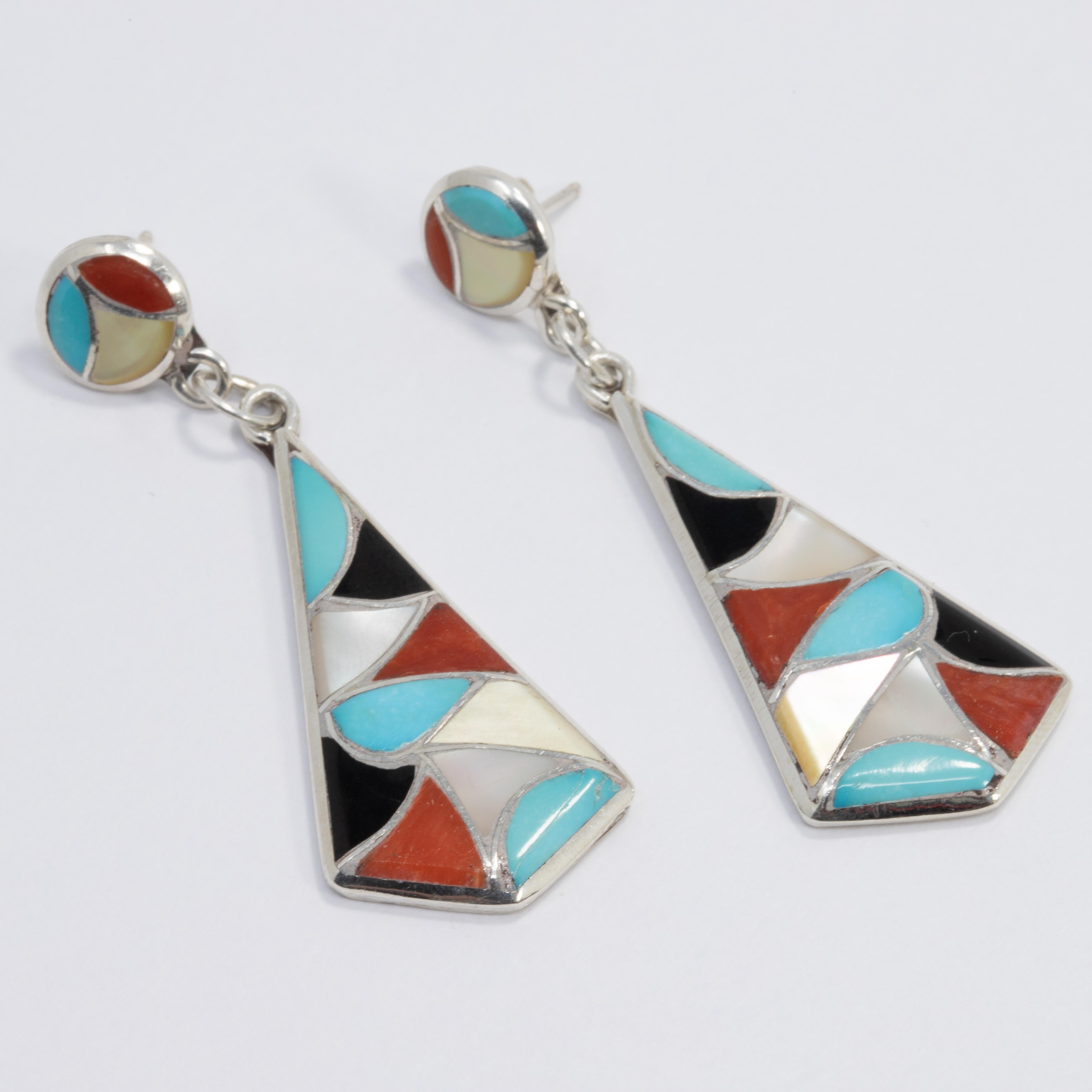 A pair of Native American Zuni dangling earrings featuring mosaic-style turquoise, coral, jet, and mother of pearl inlays set in a sterling silver setting. Colorful dangling earrings with post backs.

Hallmarks: 925, DF