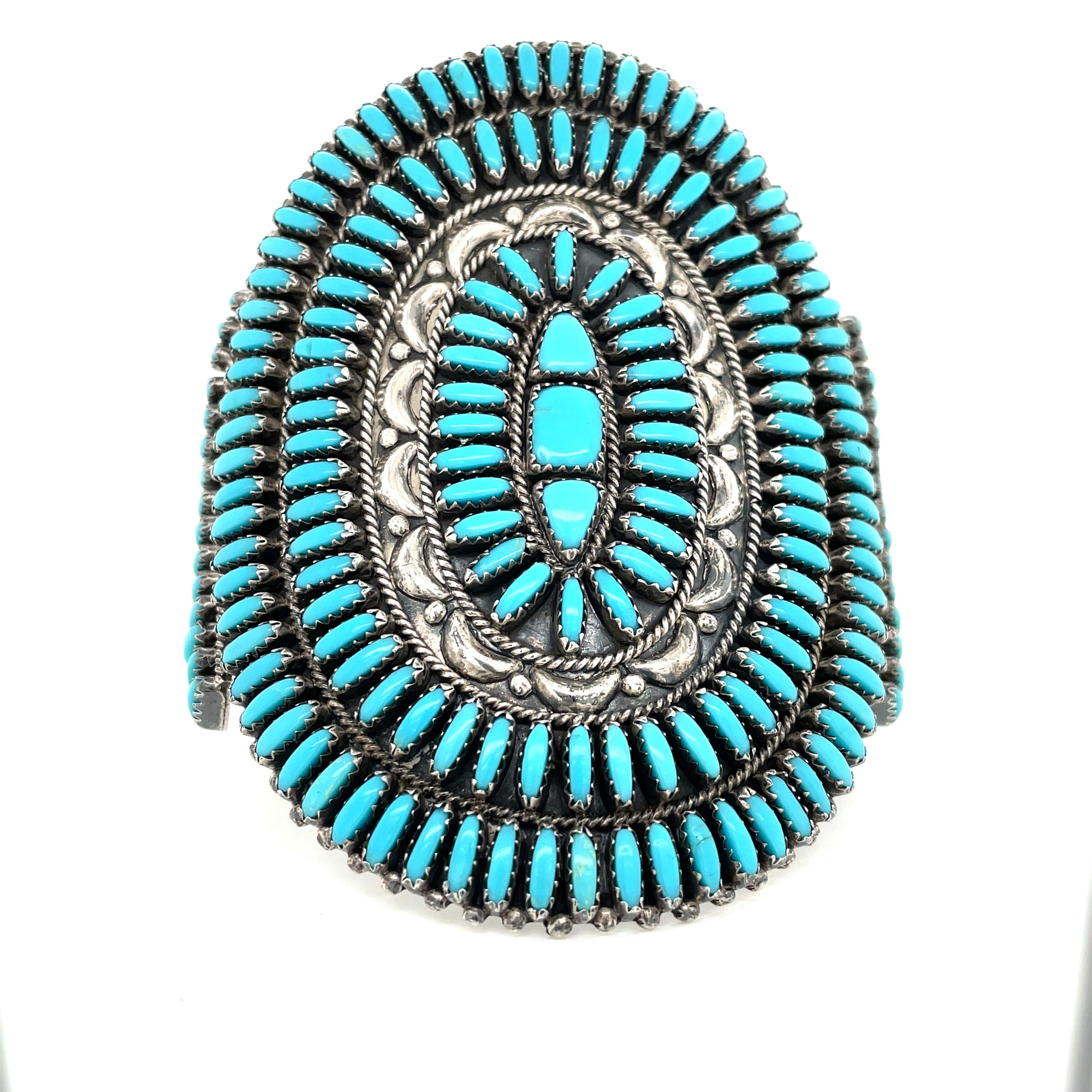 Dramatic in style, size and craftsmanship.  Exceptional Zuni lapidary skill is evident in the multiple rows of stunning needlepoint turquoise intricately handset in by Native American silversmiths. Unique to the piece is a center hand crafted