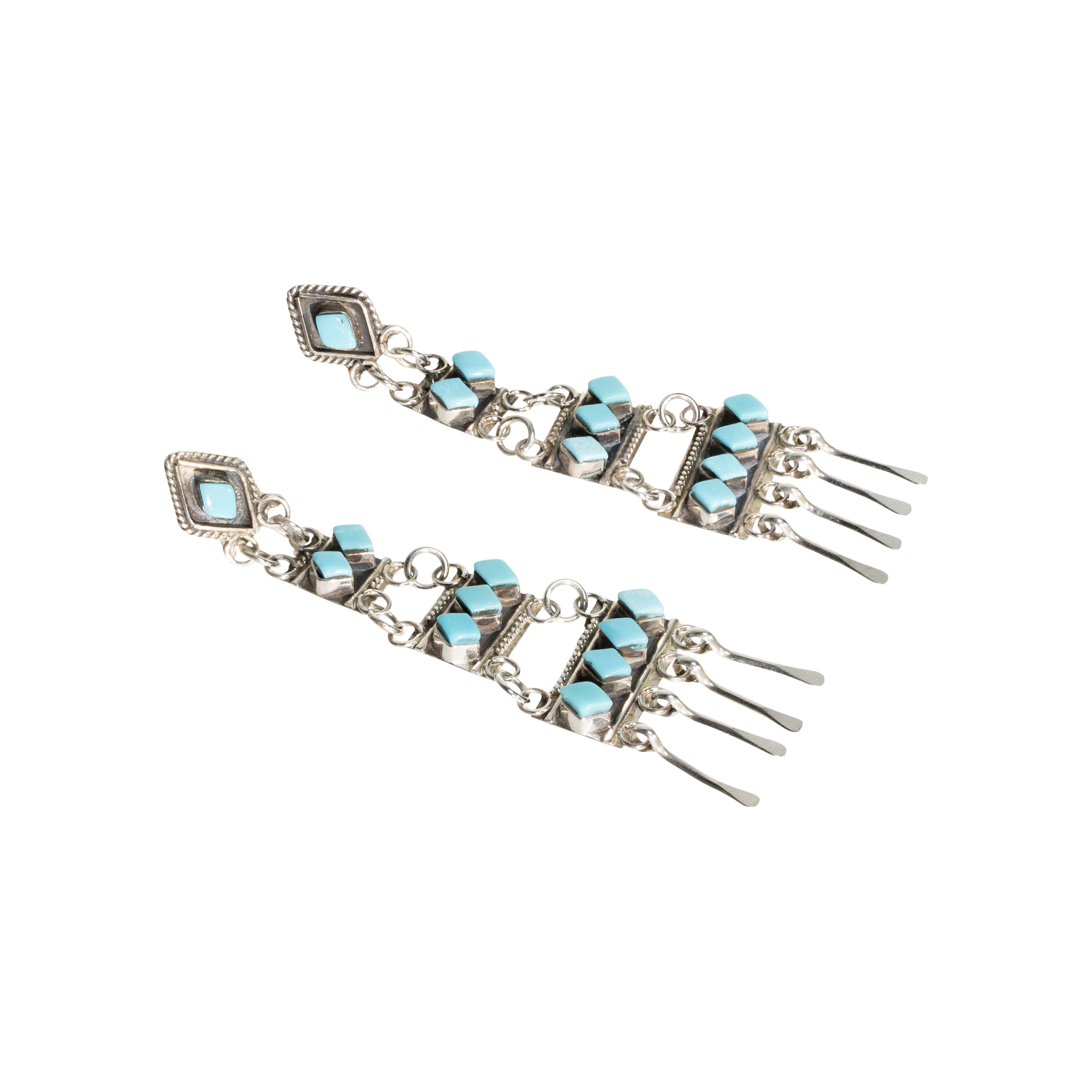 Zuni Sleeping Beauty turquoise and sterling earrings. Post backs with ten clear Sleeping Beauty stones set in shadow box with twisted rope borders ending in silver spoon drops. Lightweight and eye catching. 

PERIOD: Late 20th Century
ORIGIN: