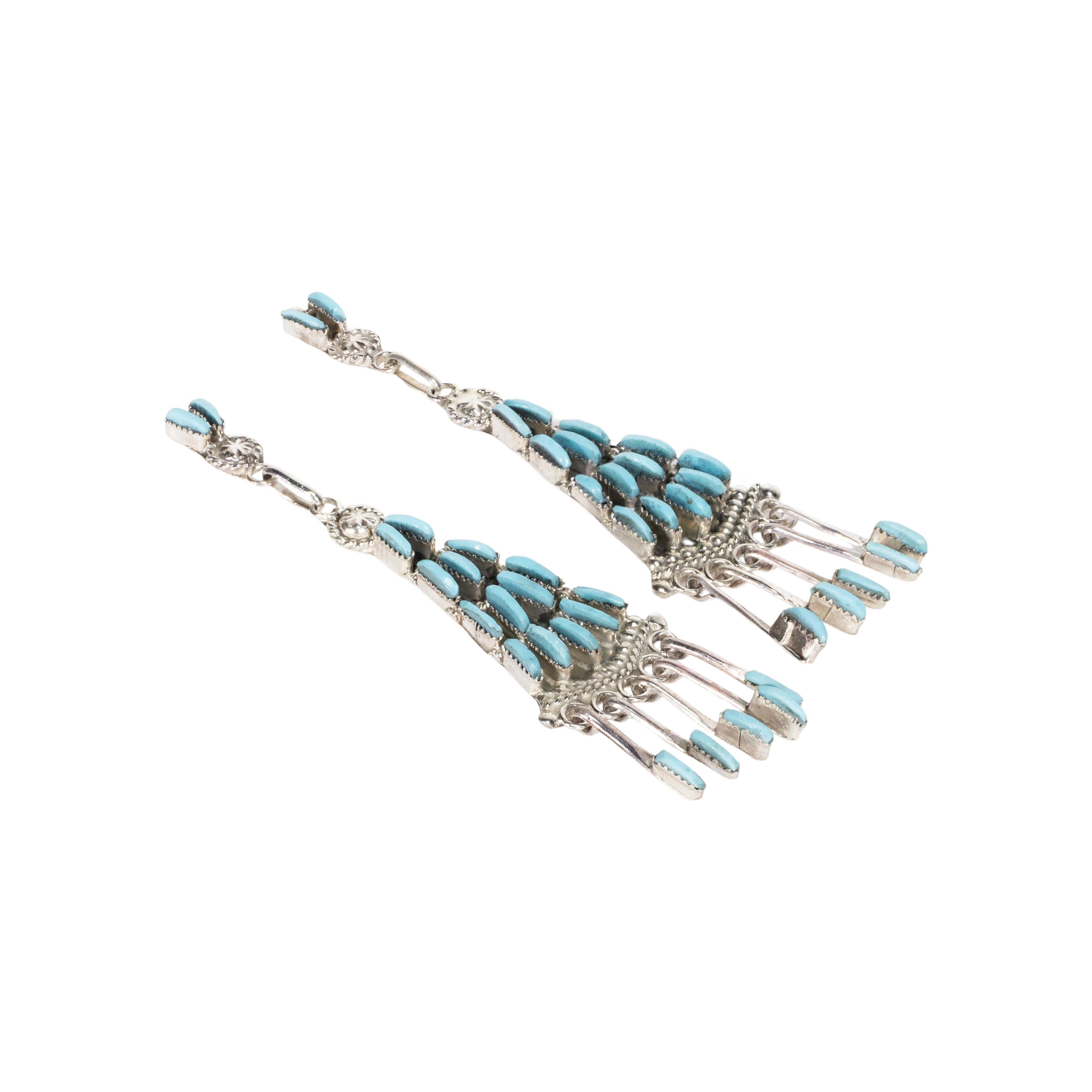 Zuni Sleeping Beauty turquoise and sterling earrings. Lightweight sterling post backs with 21 clear Sleeping Beauty stones set in shadow box with twisted rope borders ending in silver spoon drops with turquoise tips. Nice shiny patina. 

PERIOD:
