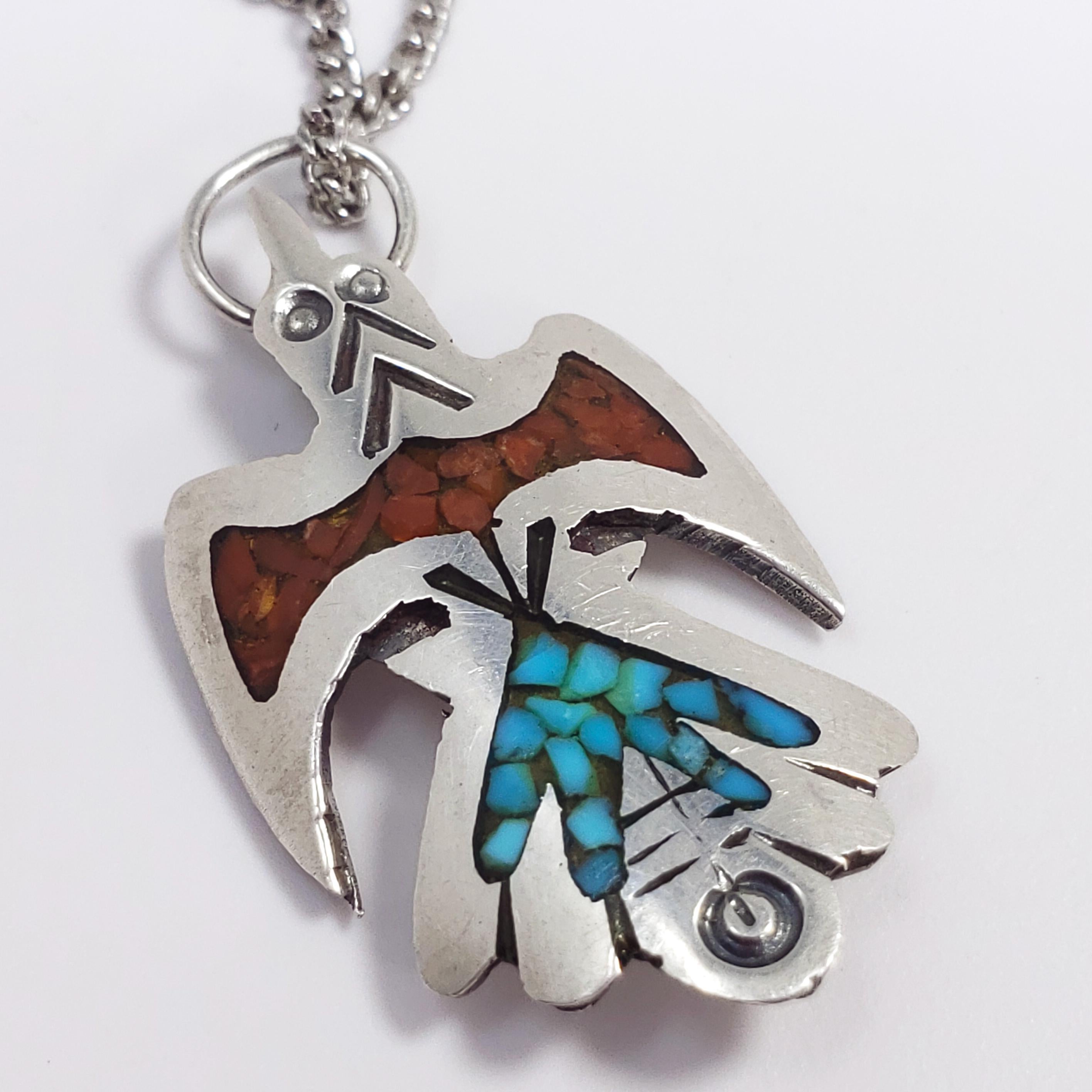 A Zuni hawk/bird pendant accented with black enamel and turquoise & coral inlays on a fine silver chain. Traditional Native American design.

Dimensions:
Pendant L 2.7 x W 1.6 cm, Necklace - 52 cm

Weight: 4.4 g

Hallmarks:
Pendant - arrowhead