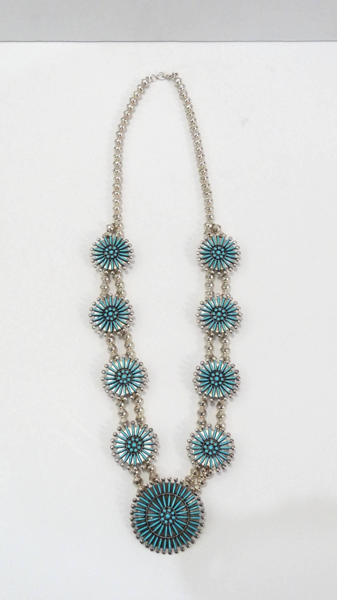 The most incredible squash blossom style necklace from the Zuni Native American tribe! Made of a quality sterling silver and inlayed with dozens of needle point cut turquoise stones, in intricate medallion patterns. Medallions strung through with