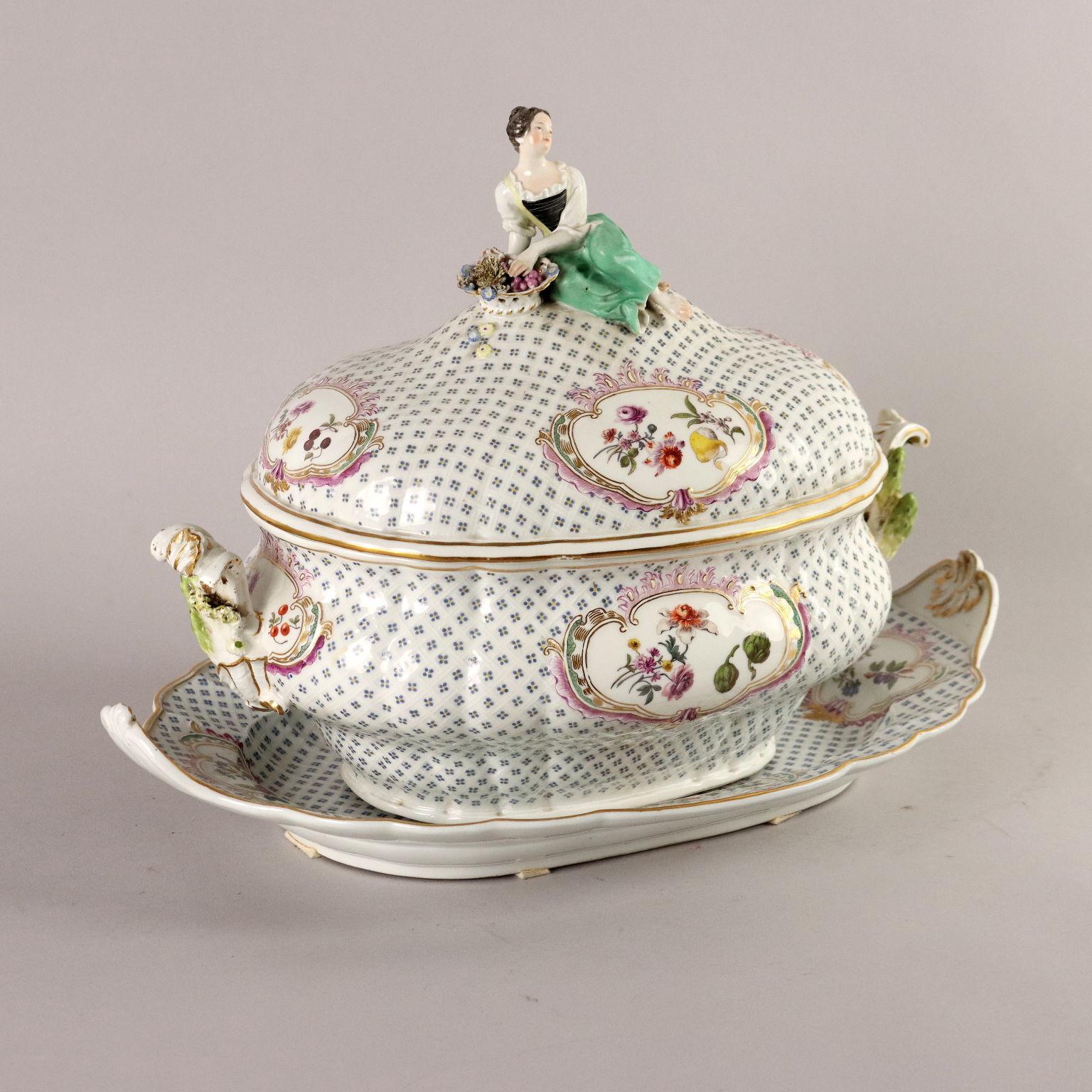 Soup bowl with oval-shaped dish, with two curl handles, lid grip in the form of a seated female figure, holding a fruit basket in her hands. Decorated all over the body and lid with a pattern of stylized small flowers arranged in a lattice pattern.