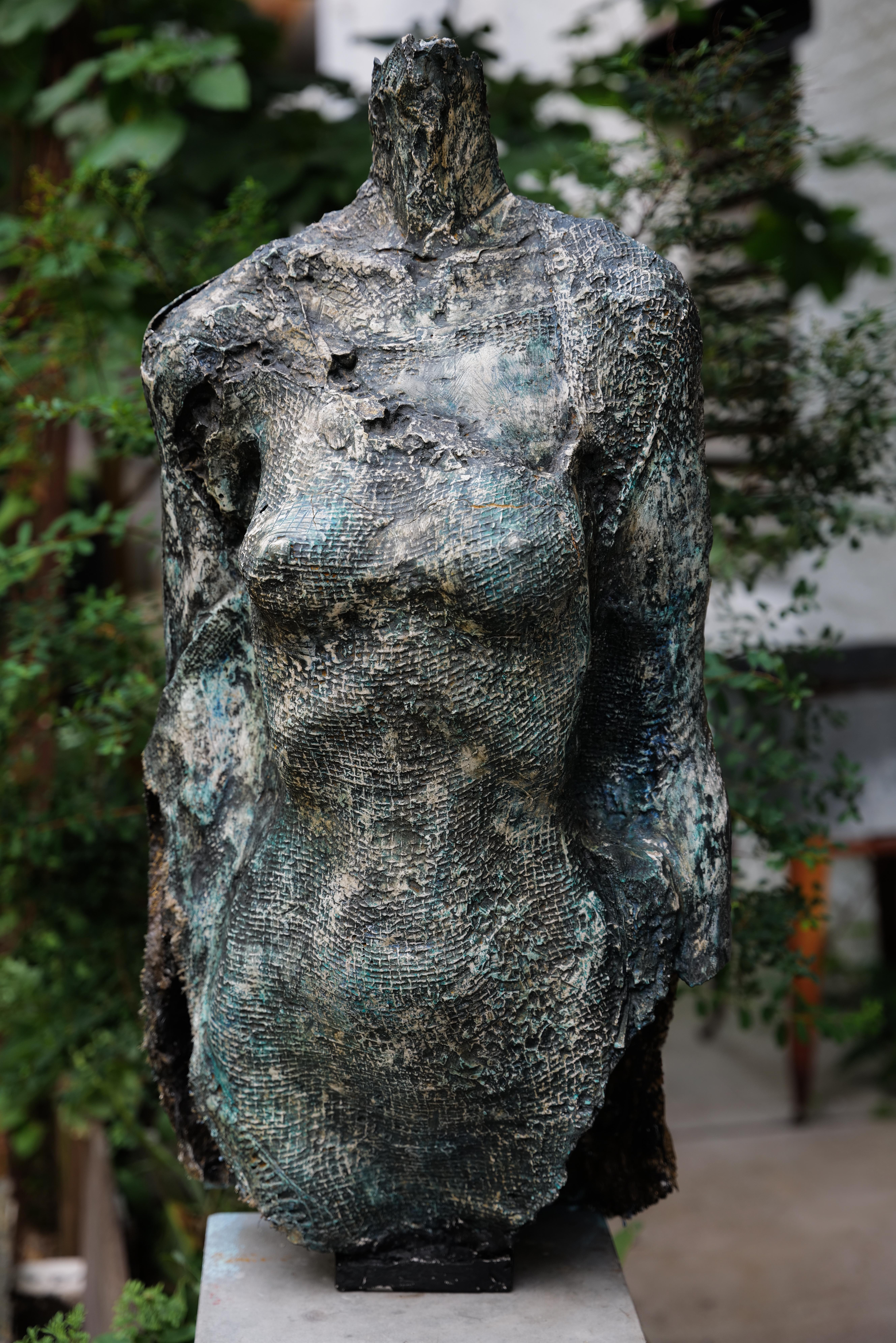À la fois imposante et contemplative, Hélène présente un torse féminin grandeur nature marqué par la rupture et l'éclat. Une fissure visible sépare l'avant et l'arrière de la forme, révélant une couche intérieure saupoudrée d'or, qui brille de