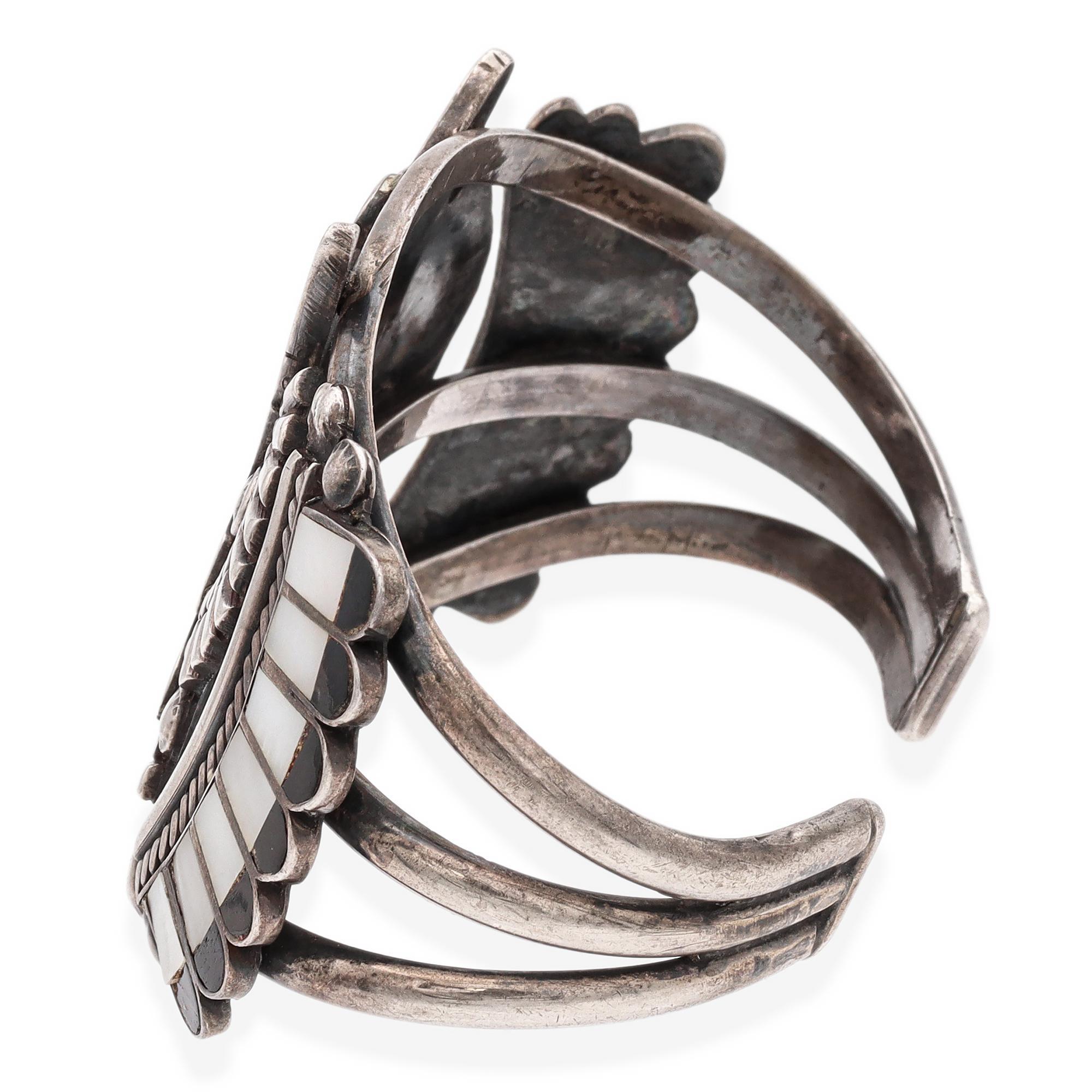 This unique bracelet showcases intricate inlay work with vibrant stones, creating a bold and colorful design. Expertly crafted, the geometric and symmetrical patterns highlight the artisan's attention to detail. The bracelet's sturdy structure
